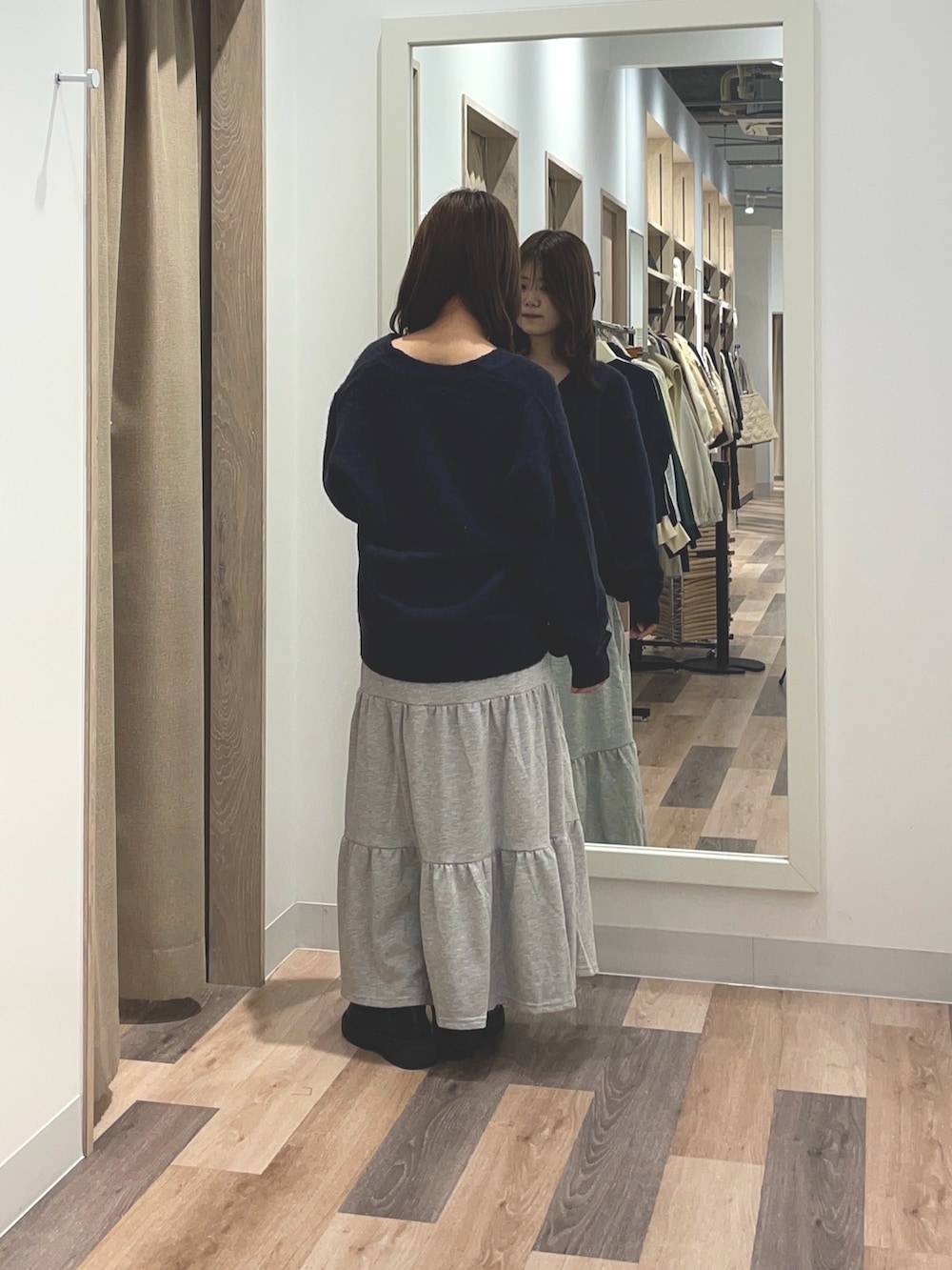 オレンジ系のカーディガン/ボレロ、ブルー系のスカートを着用したレディースの秋コーディネートの3枚目の写真