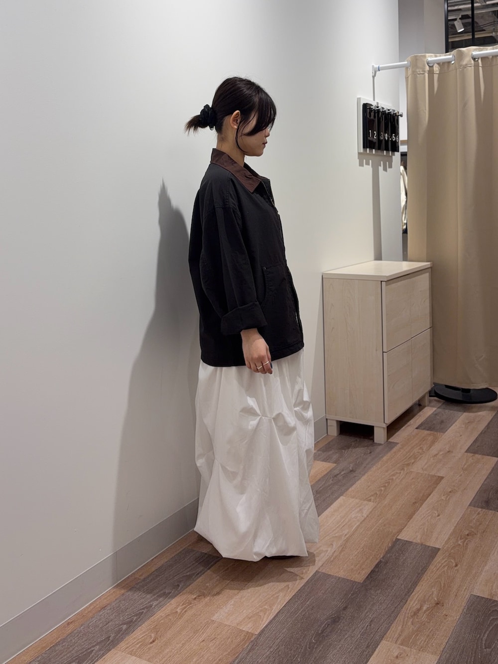 ブラック系のブルゾン、ホワイト系のスカートを着用したレディースの春コーディネートの2枚目の写真