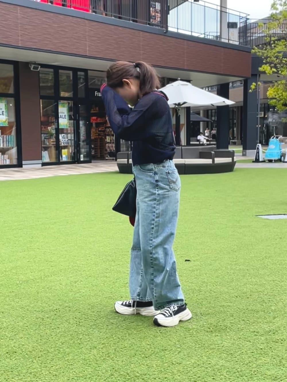 ブルー系のデニムパンツ、ブルー系のカーディガン/ボレロ、レッド系のキャップを着用したレディースの夏コーディネートの2枚目の写真