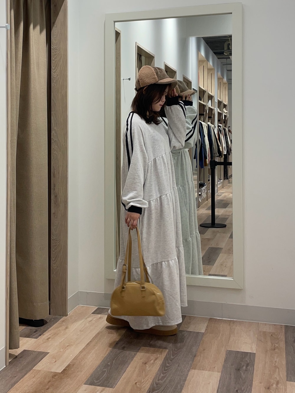 グレー系のワンピース、ブラウン系のボストンバッグを着用したレディースの秋コーディネートの2枚目の写真