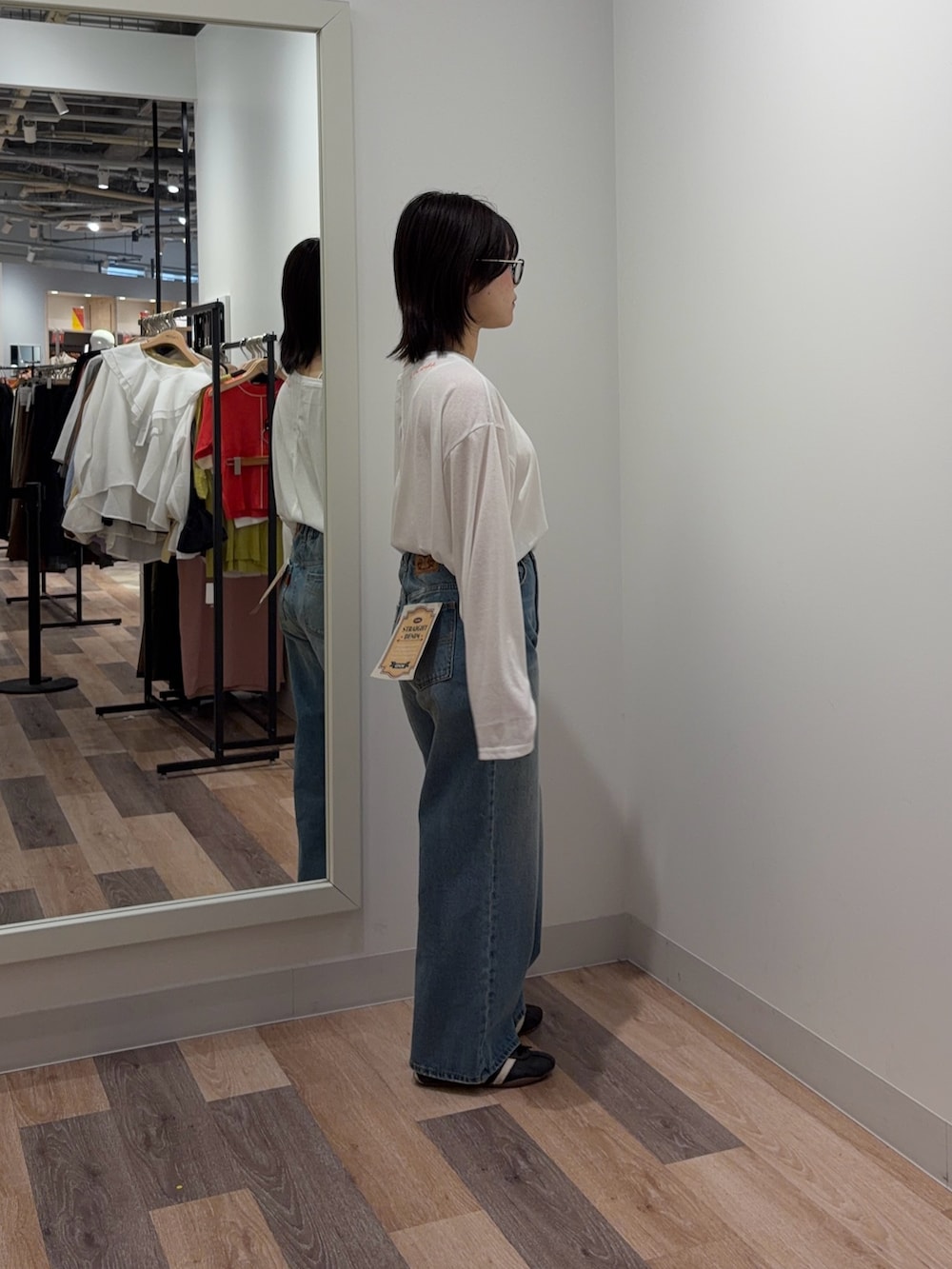 ホワイト系のキャミソール、ホワイト系のTシャツ/カットソー、ブルー系のデニムパンツを着用したレディースの春コーディネートの2枚目の写真