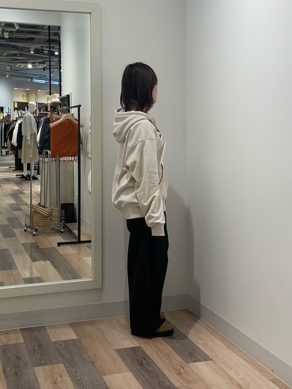 ホワイト系のパーカー、ブラック系のスラックスを着用したレディースの冬コーディネートの2枚目の写真