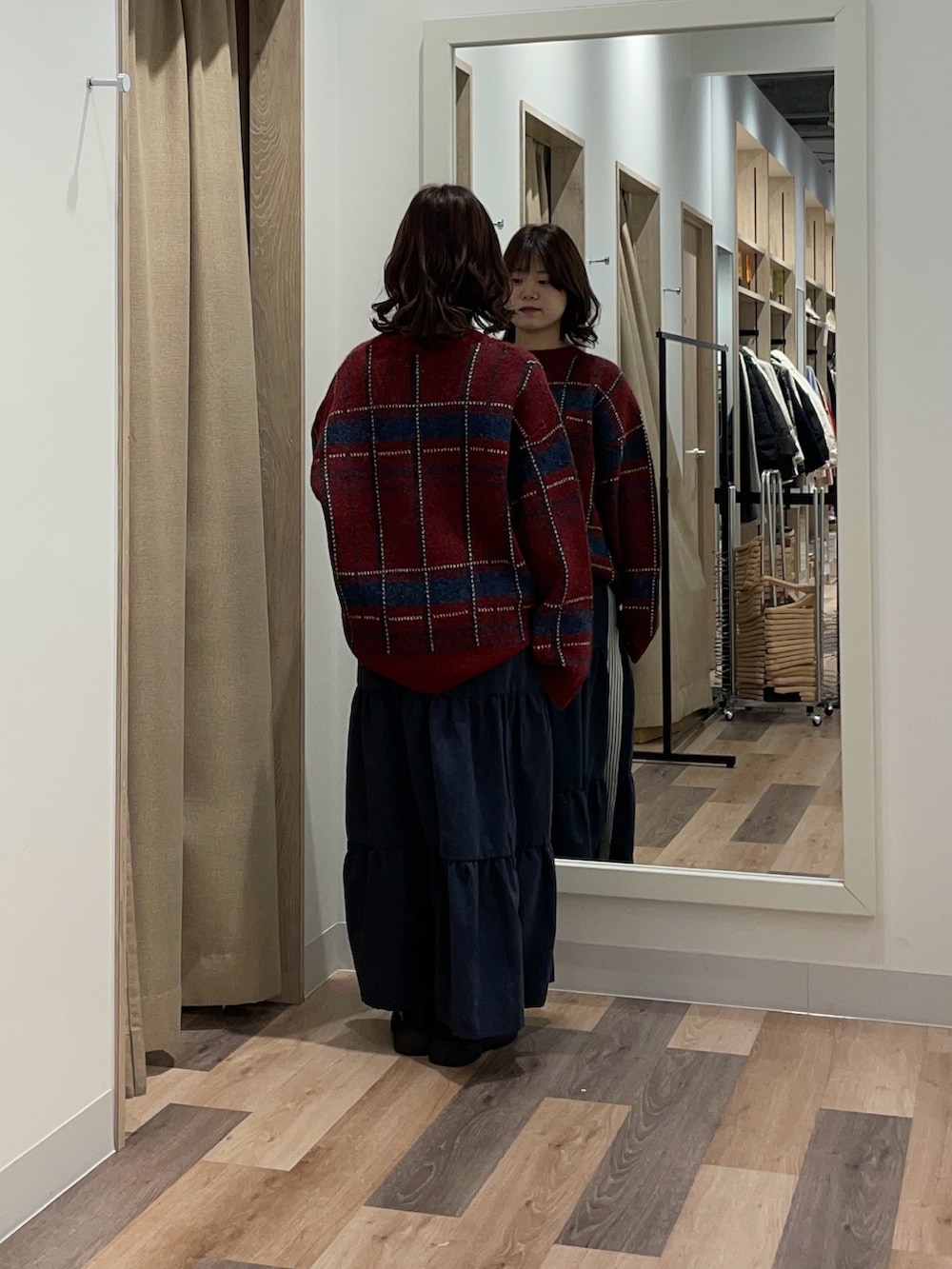 レッド系のニット/セーター、ブルー系のスカートを着用したレディースの冬コーディネートの3枚目の写真