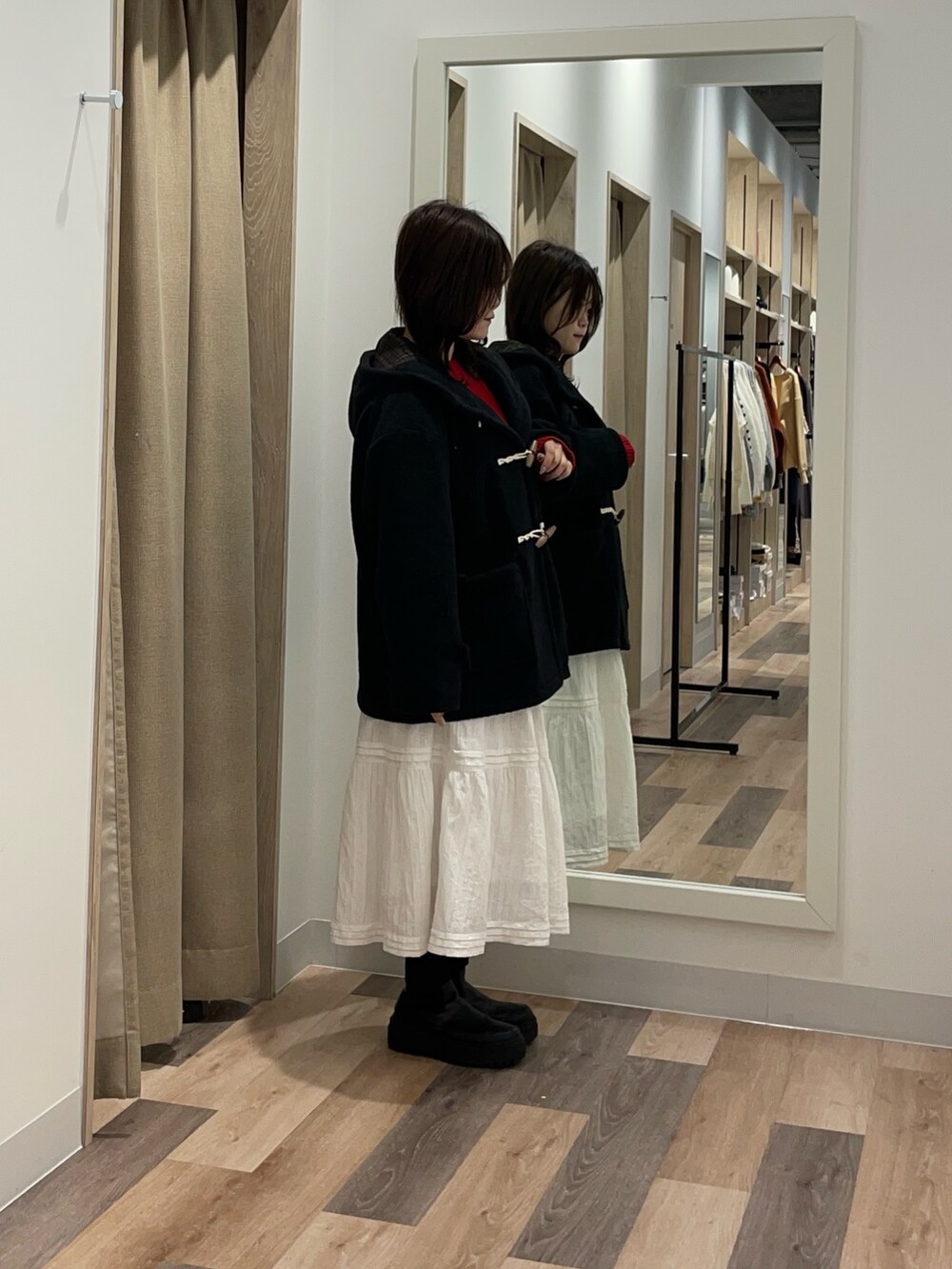 ブラック系のその他アウター、レッド系のニット/セーター、ホワイト系のスカートを着用したレディースの秋コーディネートの2枚目の写真