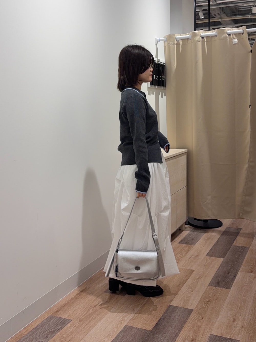 グレー系のカーディガン/ボレロ、ホワイト系のスカート、シルバー系のトートバッグを着用したレディースの春コーディネートの2枚目の写真