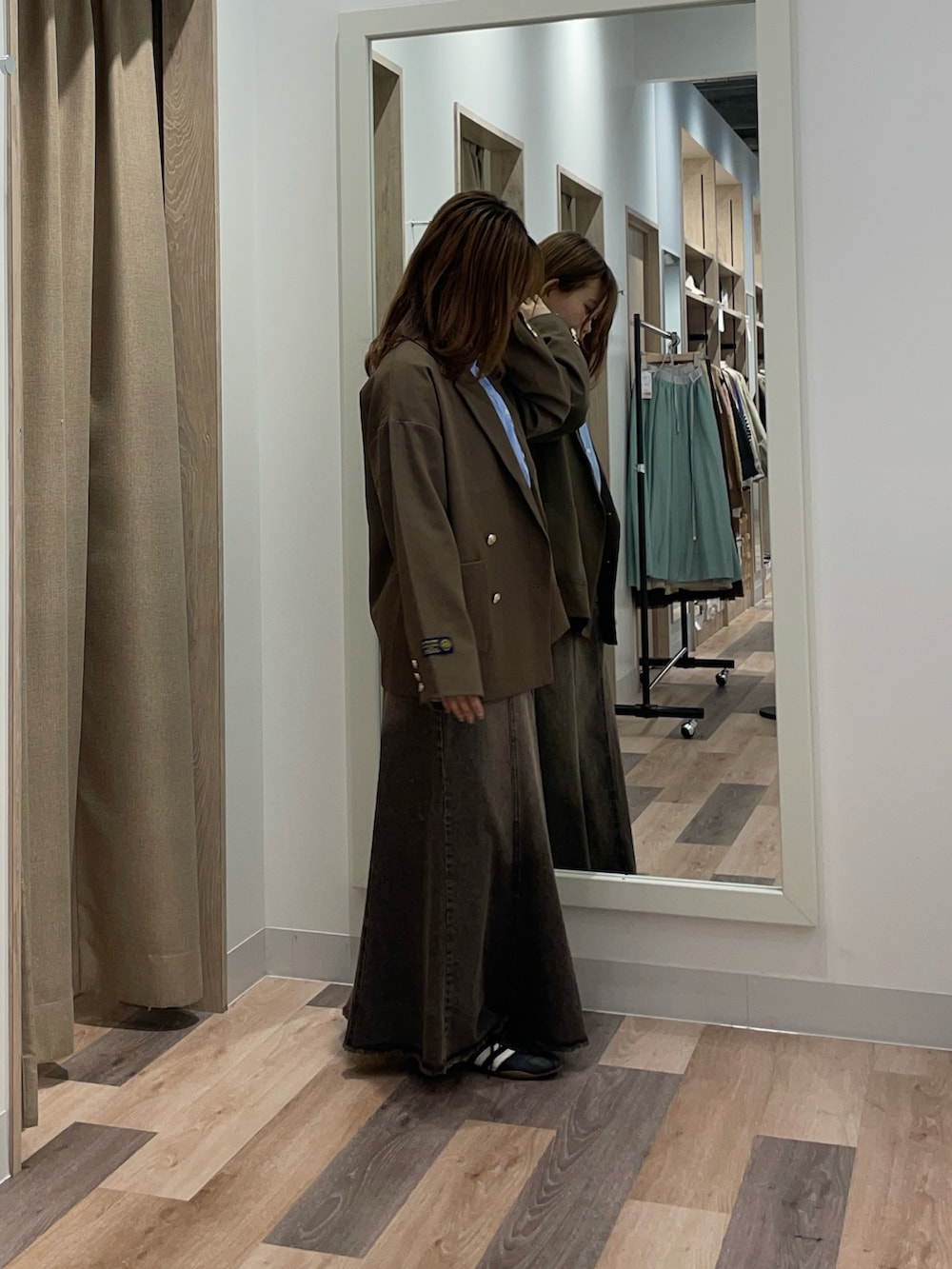 ブラウン系のテーラードジャケット、ブラック系のスカート、ブルー系のシャツ/ブラウスを着用したレディースの秋コーディネートの2枚目の写真