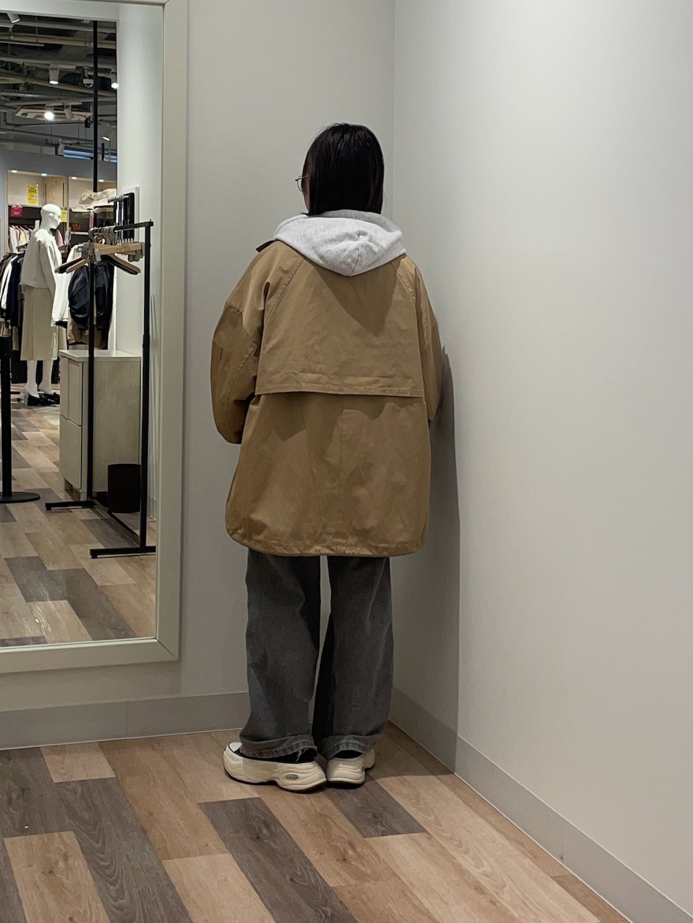 ベージュ系のトレンチコート、ホワイト系のパーカーを着用したレディースの冬コーディネートの3枚目の写真