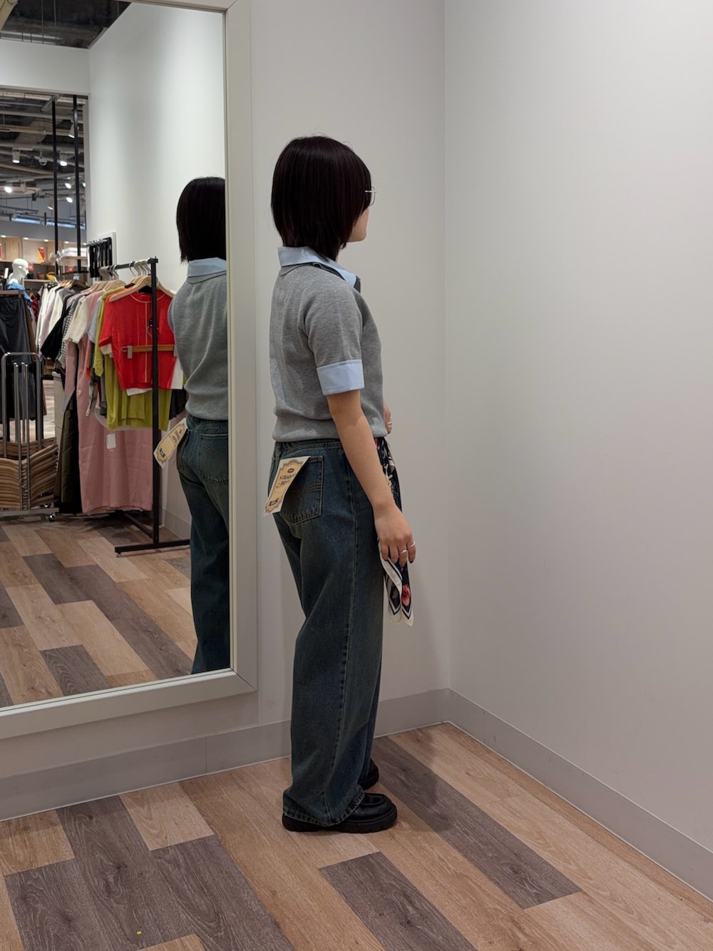 グレー系のポロシャツ、ブルー系のデニムパンツ、ブルー系のマフラーを着用したレディースの春コーディネートの2枚目の写真