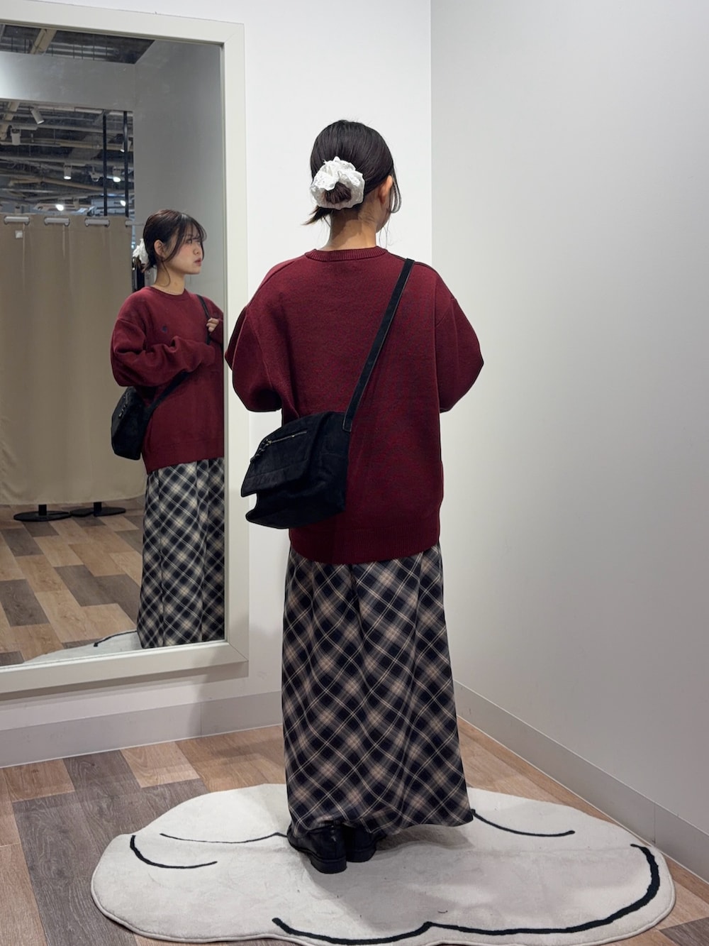 レッド系のニット/セーター、ブルー系のスカート、ブラック系のショルダーバッグを着用したレディースの秋コーディネートの3枚目の写真