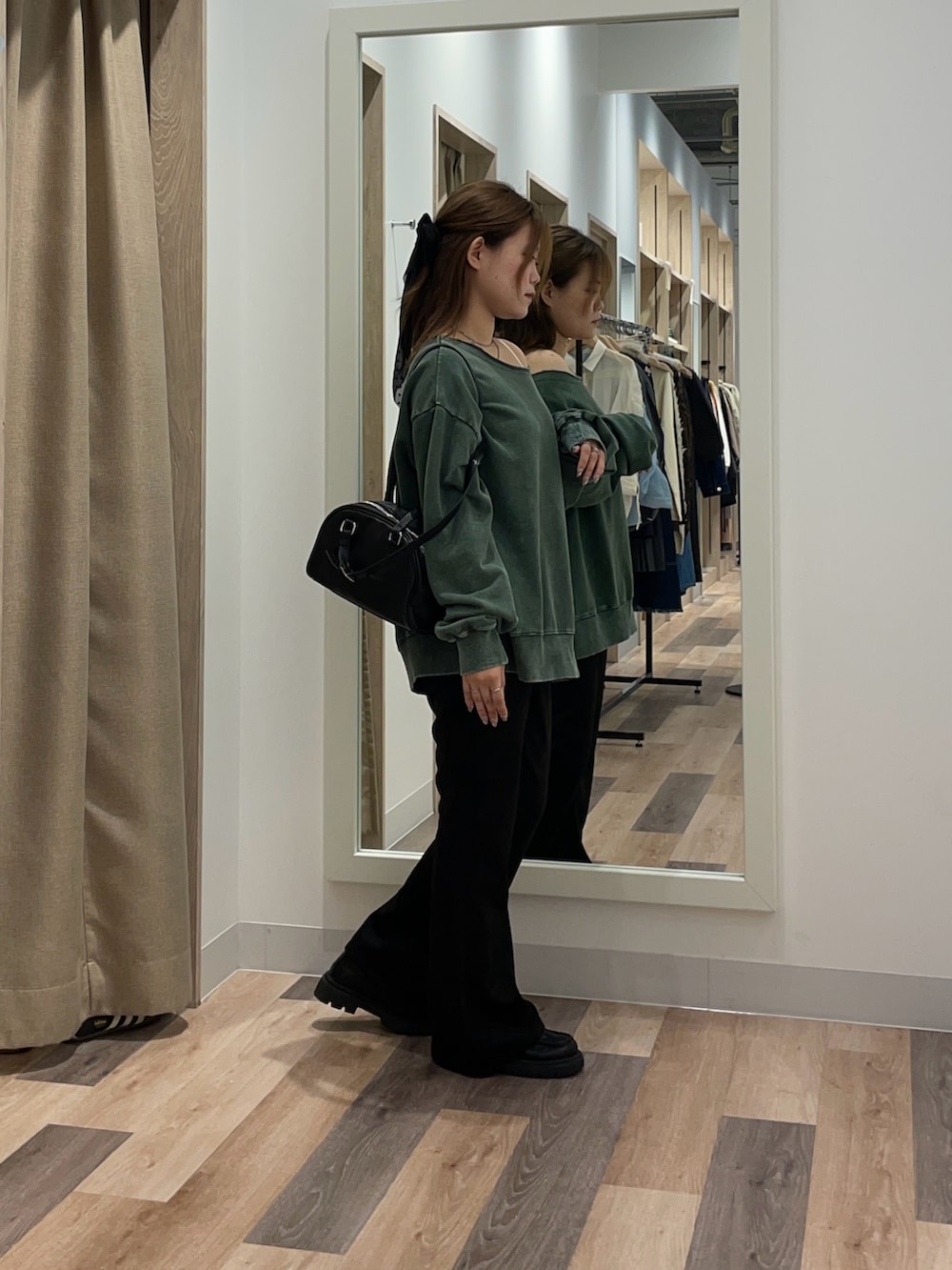 グリーン系のスウェット、ブラック系のその他パンツ、ブラウン系のボストンバッグを着用したレディースの秋コーディネートの2枚目の写真