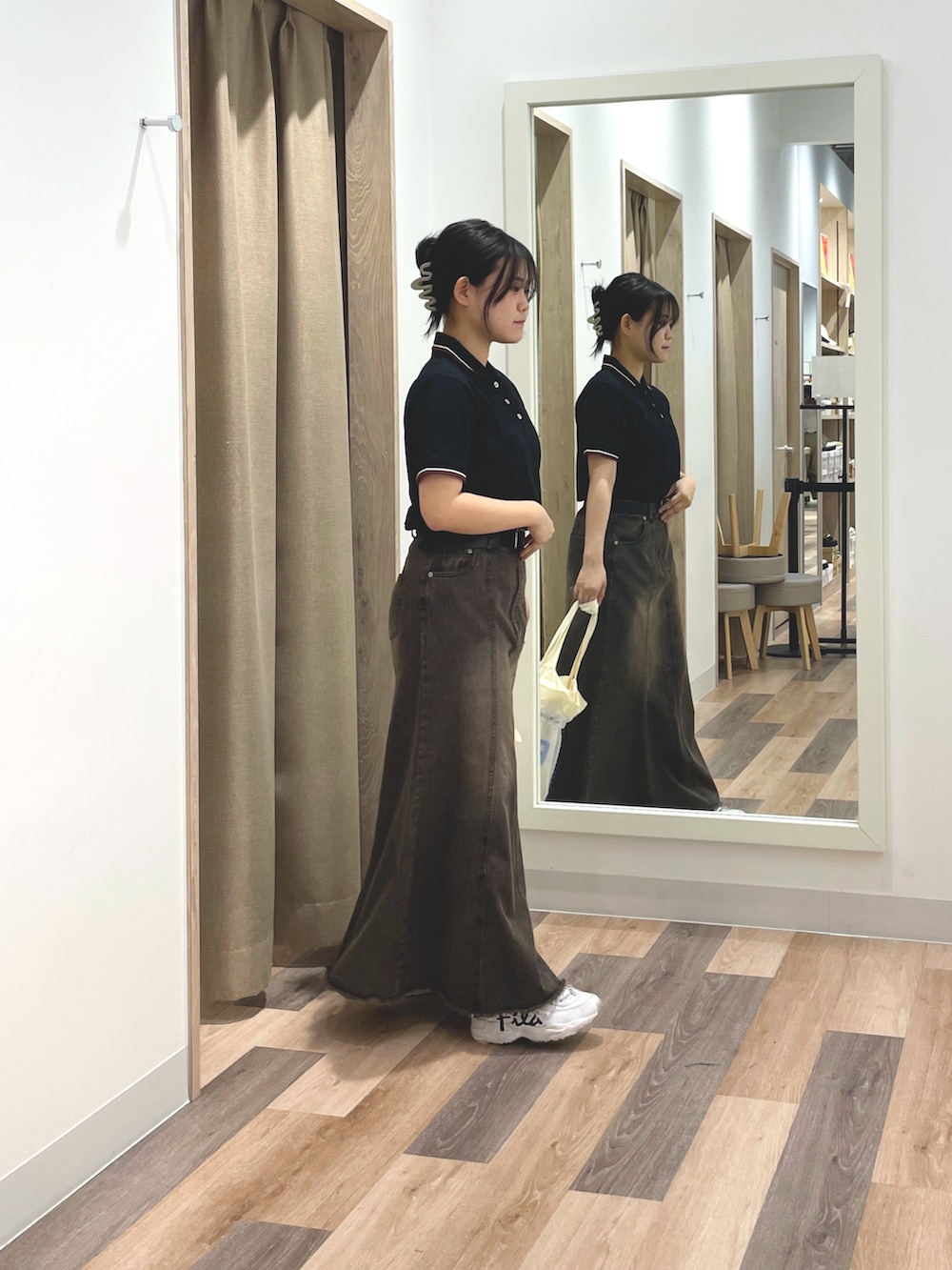 ベージュ系のポロシャツ、ブラック系のスカート、ホワイト系のトートバッグを着用したレディースの夏コーディネートの2枚目の写真