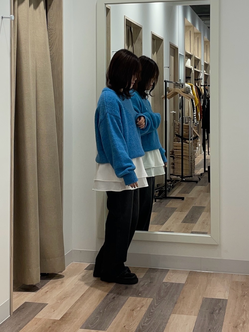 ブルー系のニット/セーター、ブラック系のデニムパンツ、ホワイト系のTシャツ/カットソーを着用したレディースの秋コーディネートの2枚目の写真