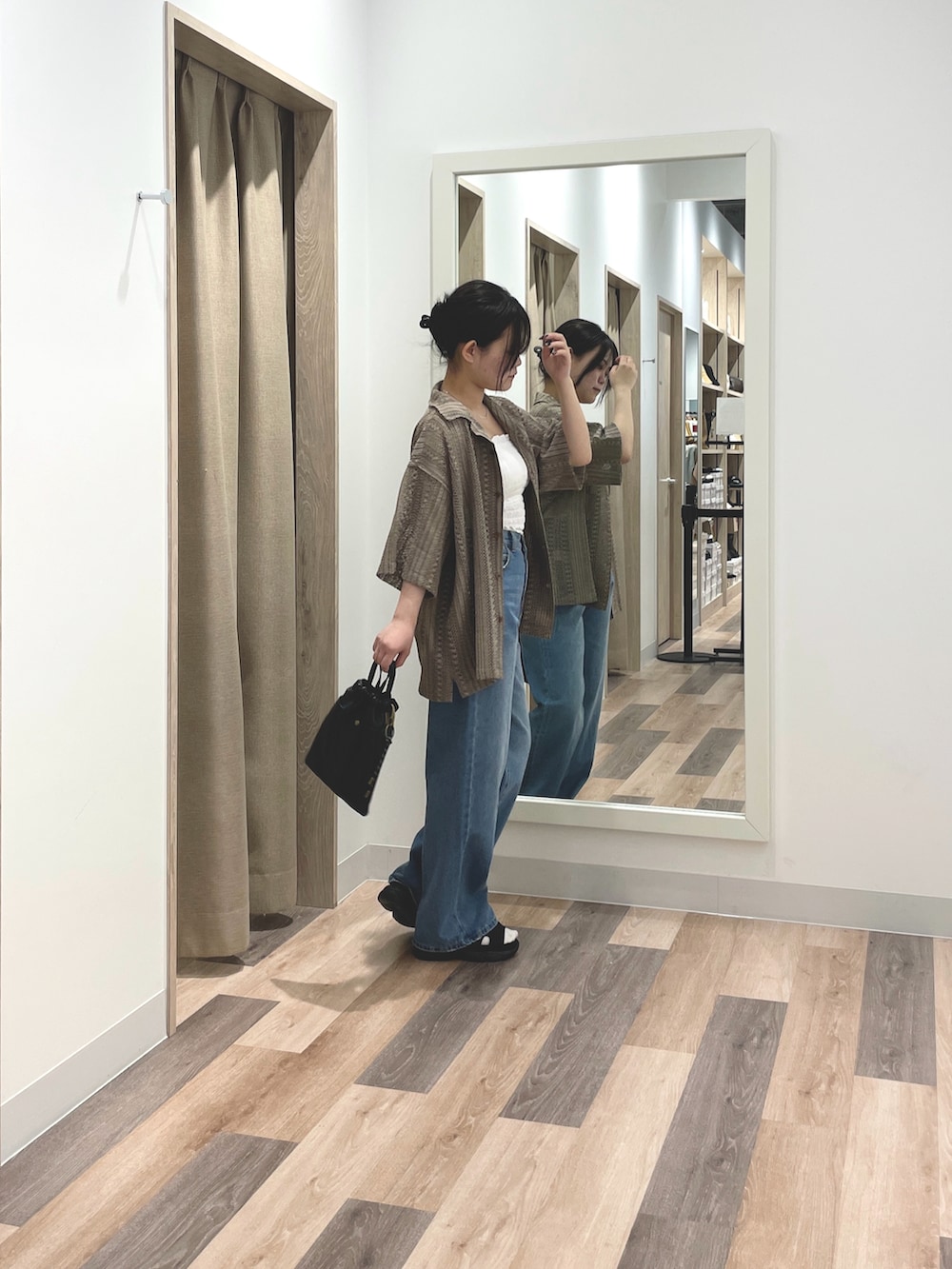 ブラウン系のシャツ/ブラウス、ブルー系のデニムパンツ、ブラック系のショルダーバッグを着用したレディースの春コーディネートの2枚目の写真