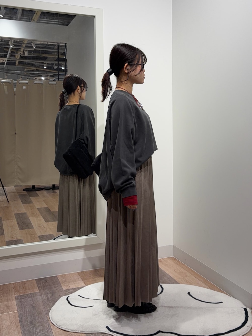 レッド系のTシャツ/カットソー、グレー系のスカート、ブラック系のショルダーバッグを着用したレディースの秋コーディネートの2枚目の写真