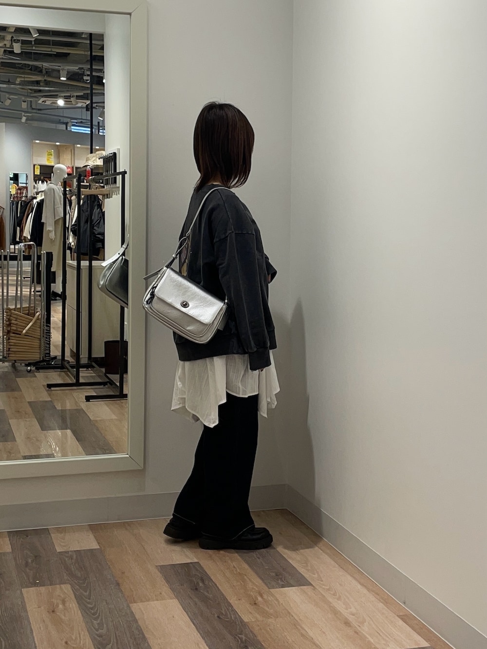 ブルー系のニット/セーター、ホワイト系のシャツ/ブラウス、シルバー系のトートバッグを着用したレディースの冬コーディネートの2枚目の写真