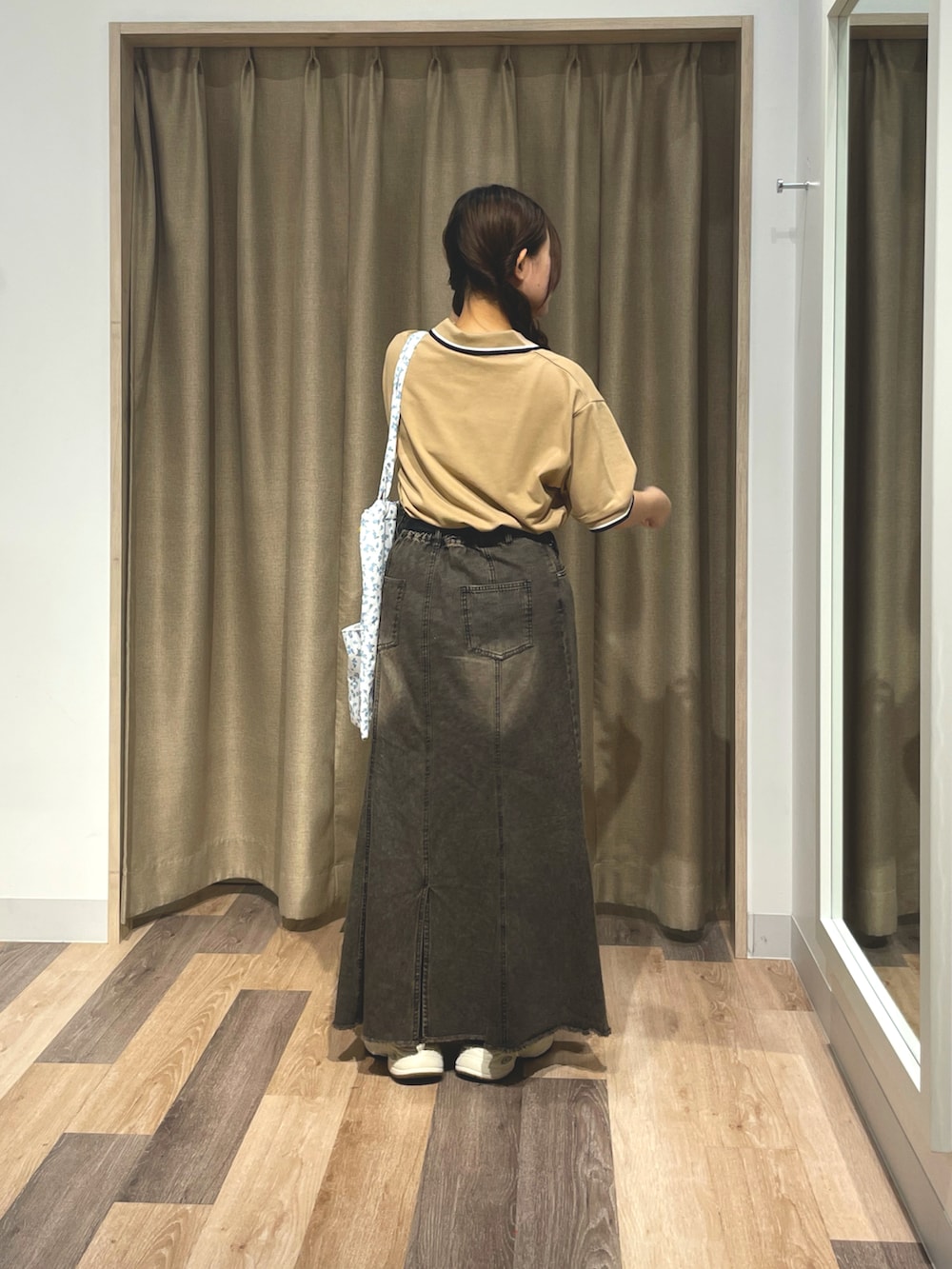 ベージュ系のポロシャツ、ブラック系のスカート、ブラック系のトートバッグを着用したレディースの夏コーディネートの3枚目の写真