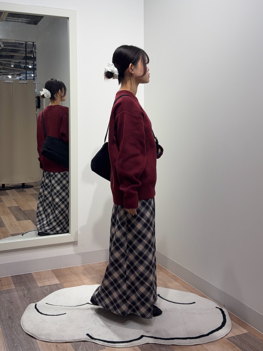 レッド系のニット/セーター、ブルー系のスカート、ブラック系のショルダーバッグを着用したレディースの秋コーディネートの2枚目の写真
