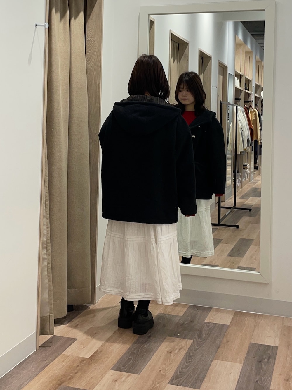 ブラック系のその他アウター、レッド系のニット/セーター、ホワイト系のスカートを着用したレディースの秋コーディネートの3枚目の写真