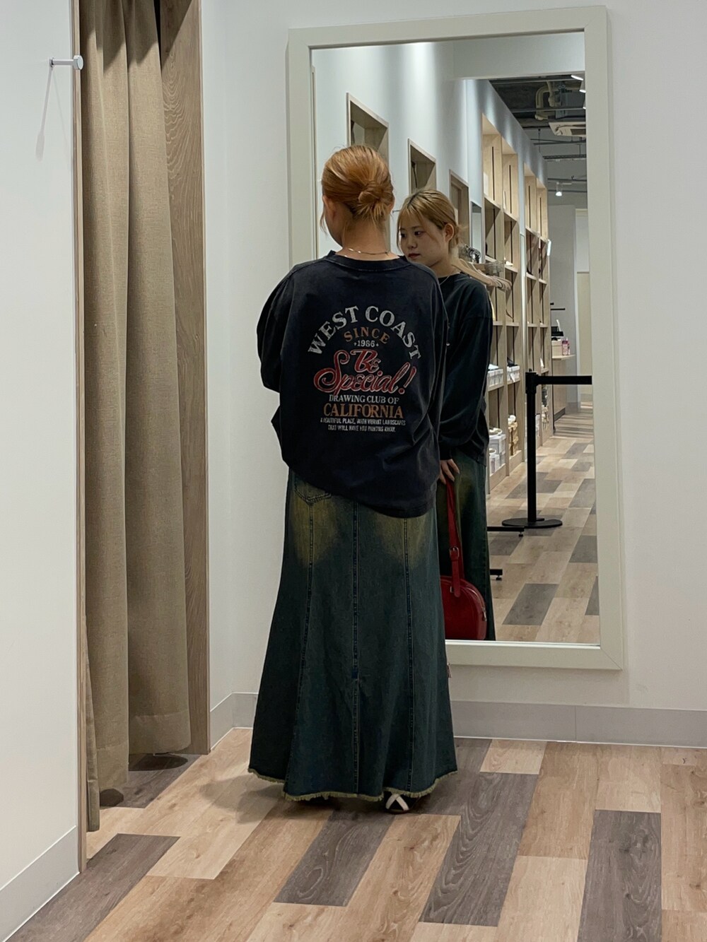 ブルー系のスカート、ブラウン系のボストンバッグ、ブラック系のTシャツ/カットソーを着用したレディースの夏コーディネートの3枚目の写真