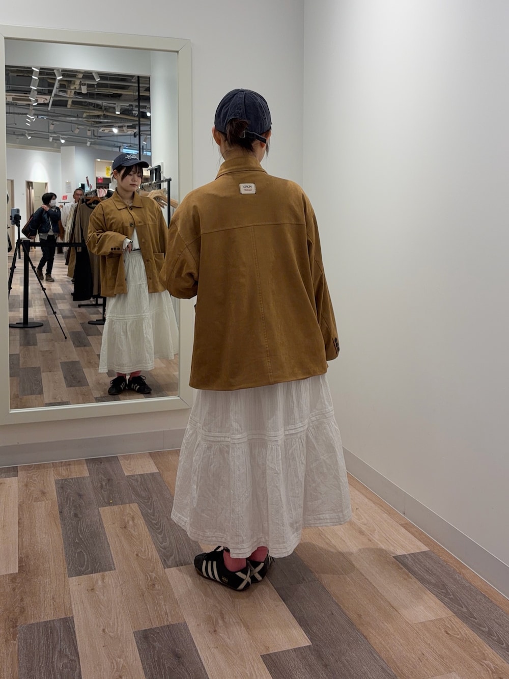 イエロー系のブルゾン、ホワイト系のスカートを着用したレディースの冬コーディネートの3枚目の写真