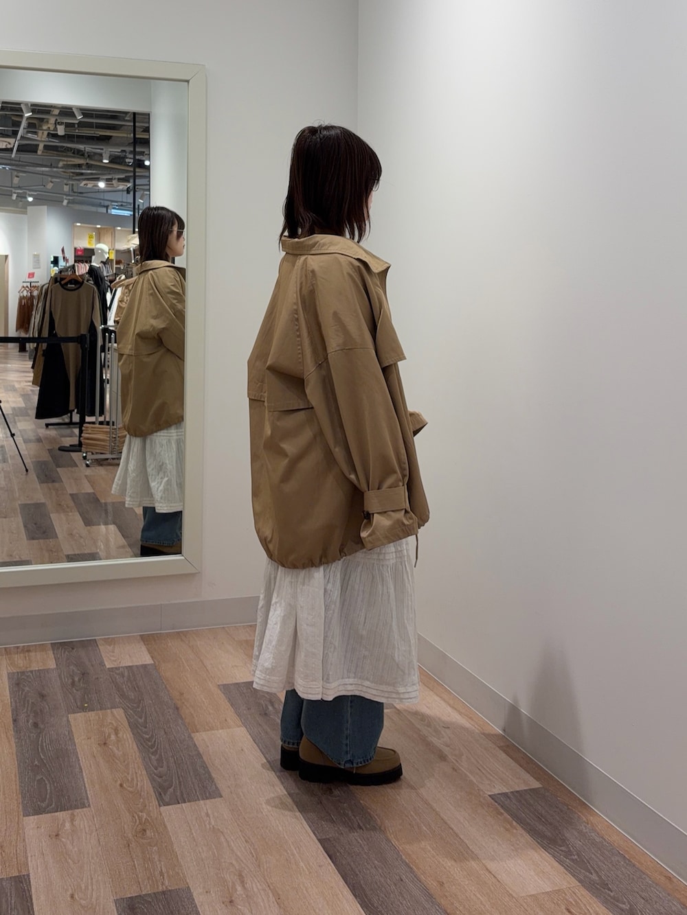 ベージュ系のトレンチコート、ピンク系のカーディガン/ボレロ、ホワイト系のスカートを着用したレディースの冬コーディネートの3枚目の写真