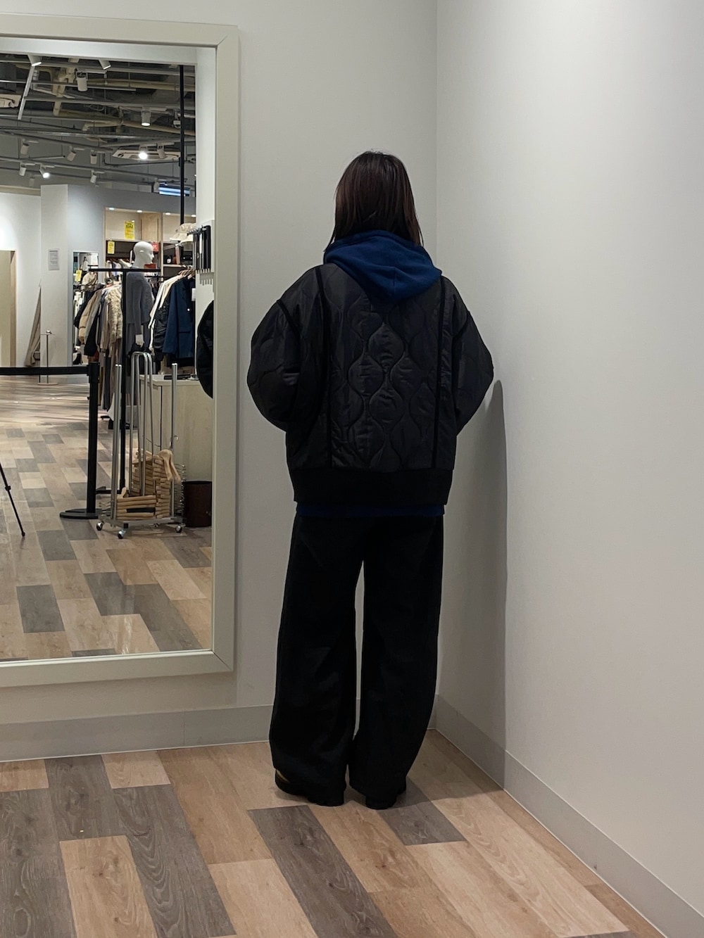 ブラック系のブルゾン、ブルー系のパーカー、ブラック系のスラックスを着用したレディースの冬コーディネートの3枚目の写真