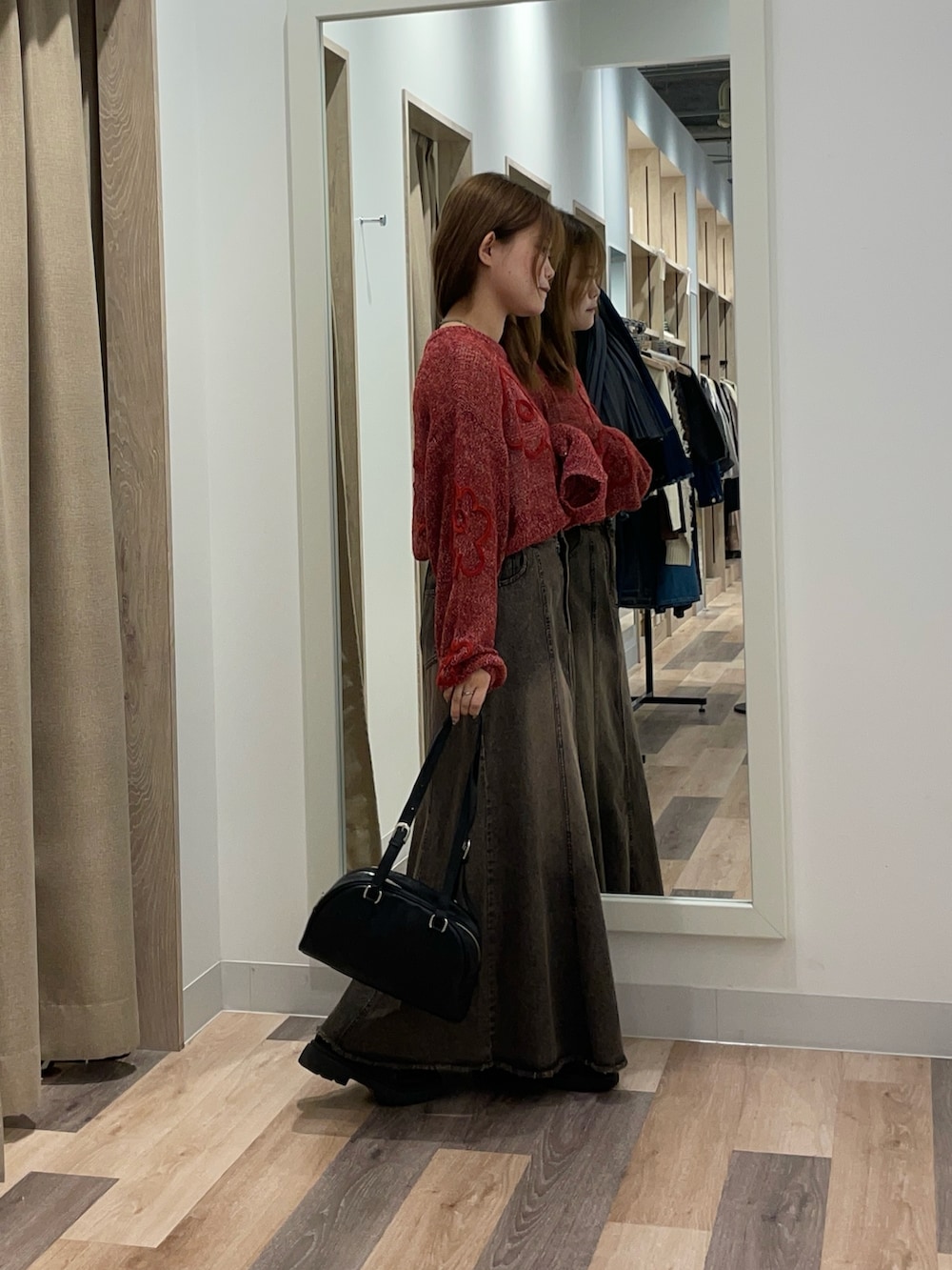 レッド系のニット/セーター、ブラック系のスカート、ブラウン系のボストンバッグを着用したレディースの秋コーディネートの2枚目の写真