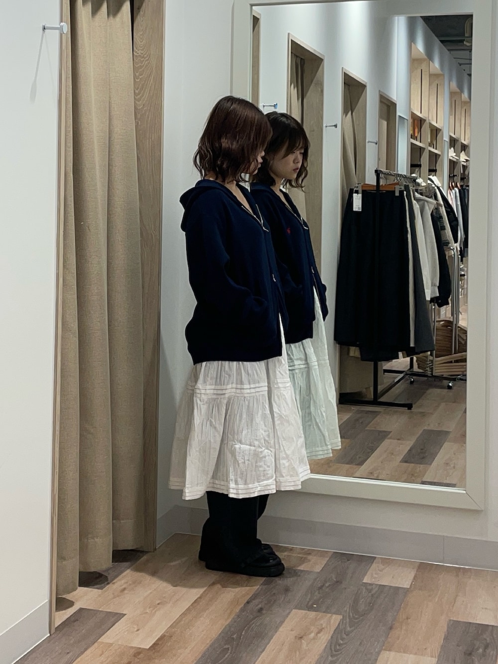 グレー系のニット/セーター、ホワイト系のスカート、ブラック系のデニムパンツを着用したレディースの冬コーディネートの2枚目の写真