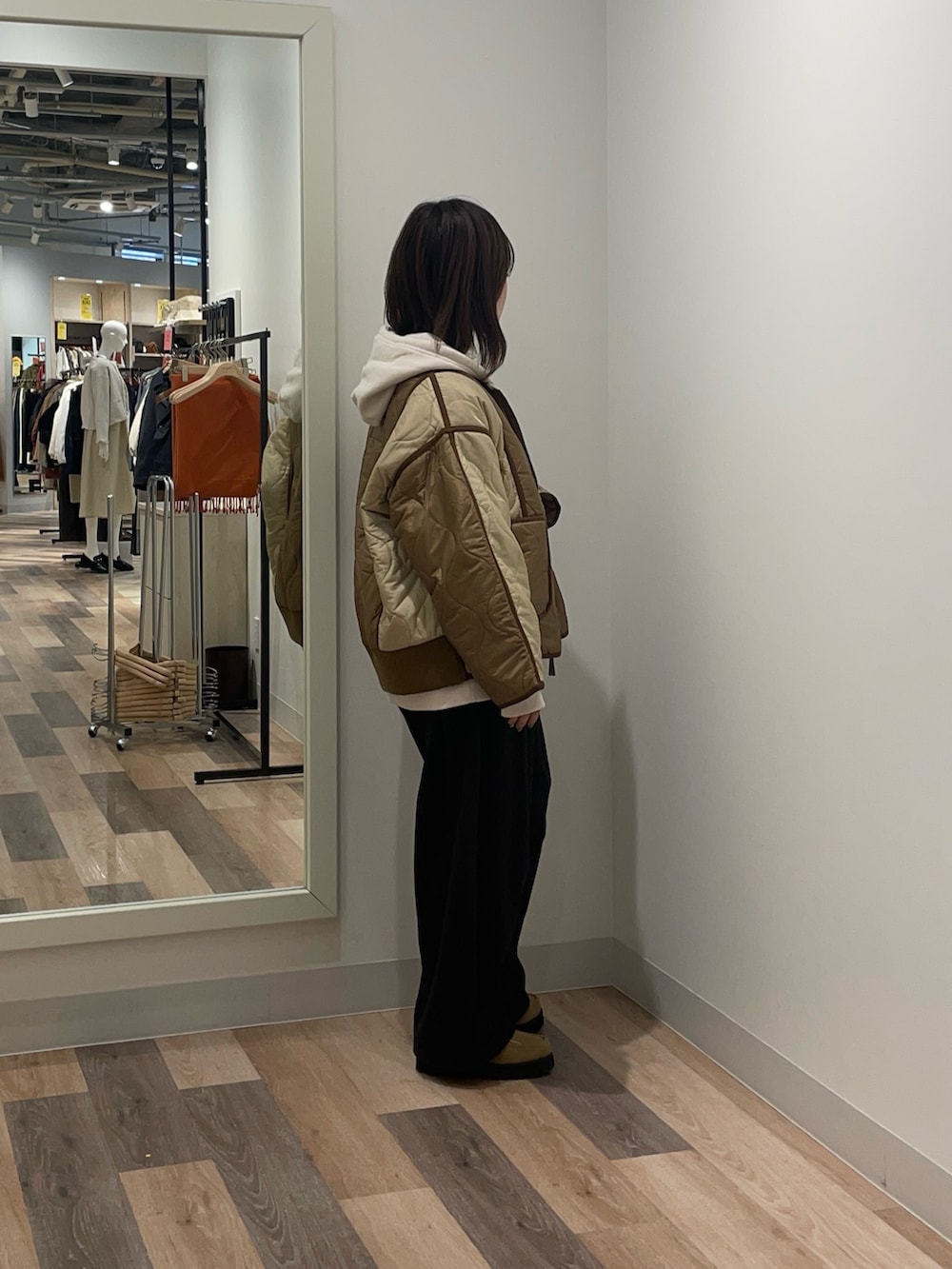 ベージュ系のブルゾン、ホワイト系のパーカー、ブラック系のスラックスを着用したレディースの冬コーディネートの2枚目の写真