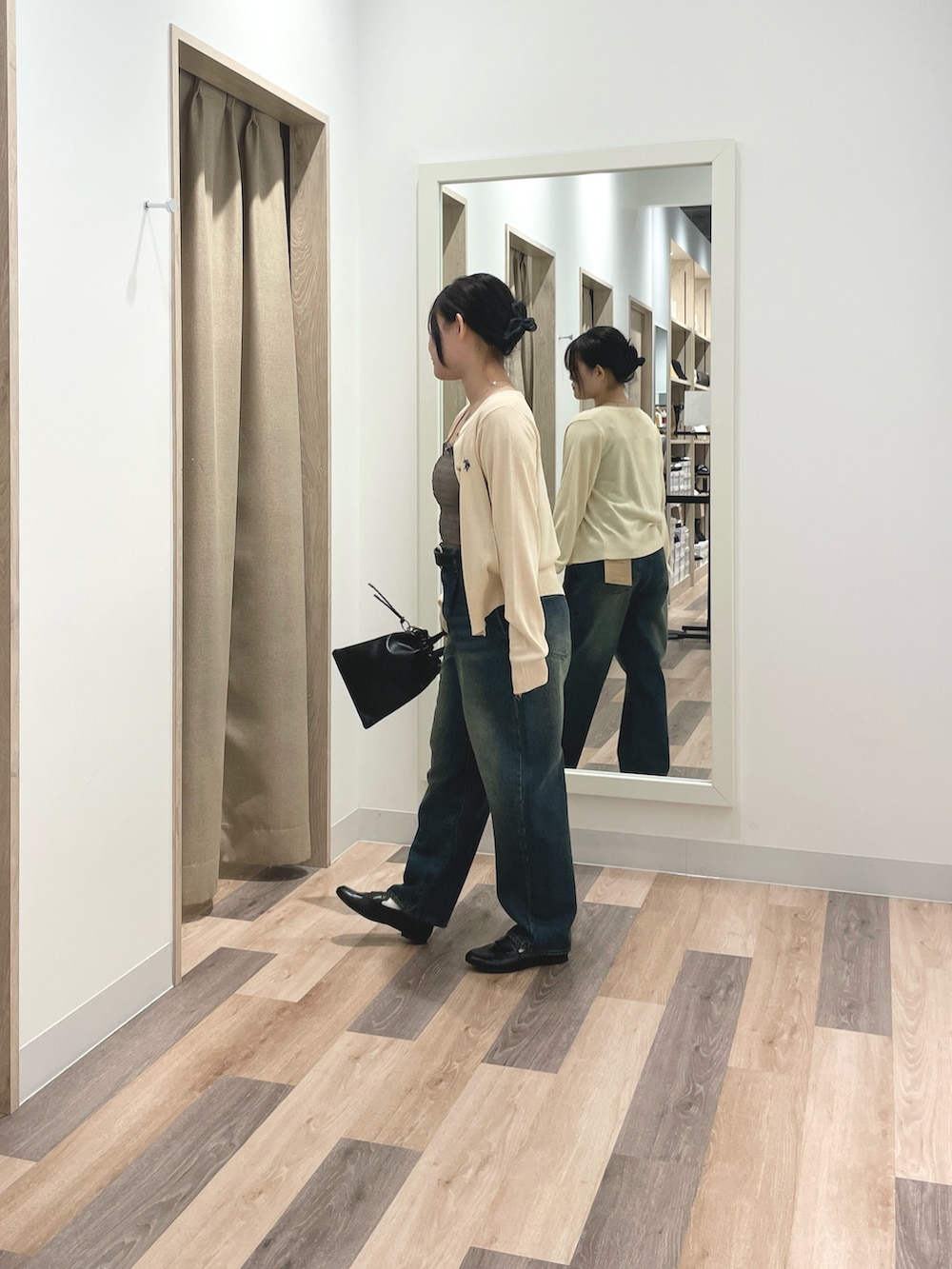 グレー系のカーディガン/ボレロ、ブルー系のデニムパンツ、ブラック系のショルダーバッグを着用したレディースの春コーディネートの2枚目の写真