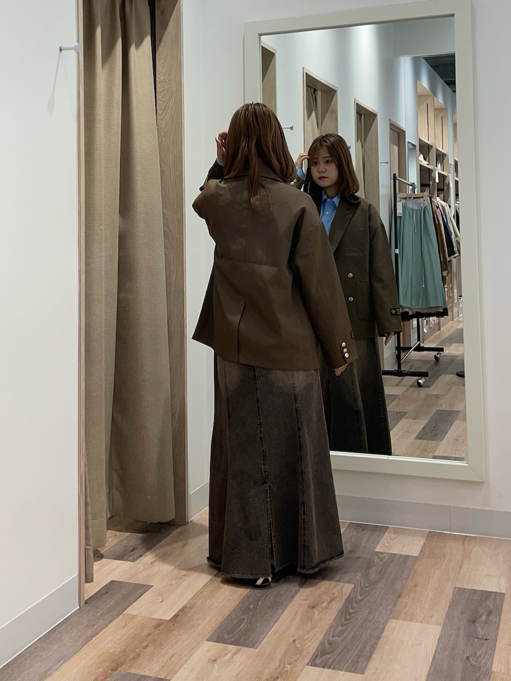 ブラウン系のテーラードジャケット、ブラック系のスカート、ブルー系のシャツ/ブラウスを着用したレディースの秋コーディネートの3枚目の写真