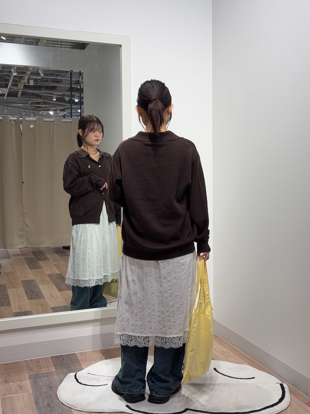 ブラウン系のカーディガン/ボレロ、ホワイト系のスカート、ブルー系のデニムパンツを着用したレディースの秋コーディネートの3枚目の写真