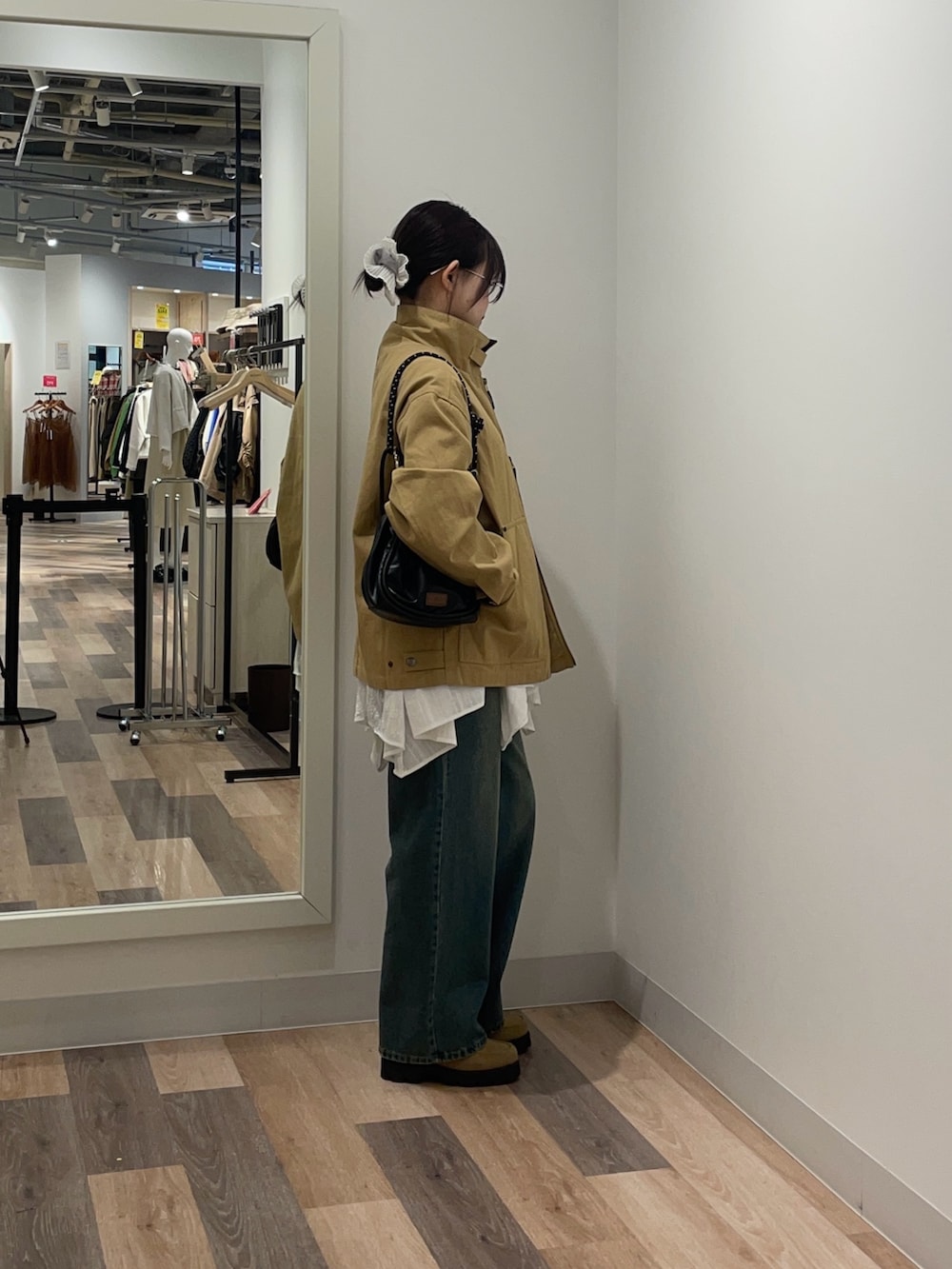 イエロー系のブルゾン、ホワイト系のシャツ/ブラウス、ブルー系のデニムパンツを着用したレディースの冬コーディネートの2枚目の写真