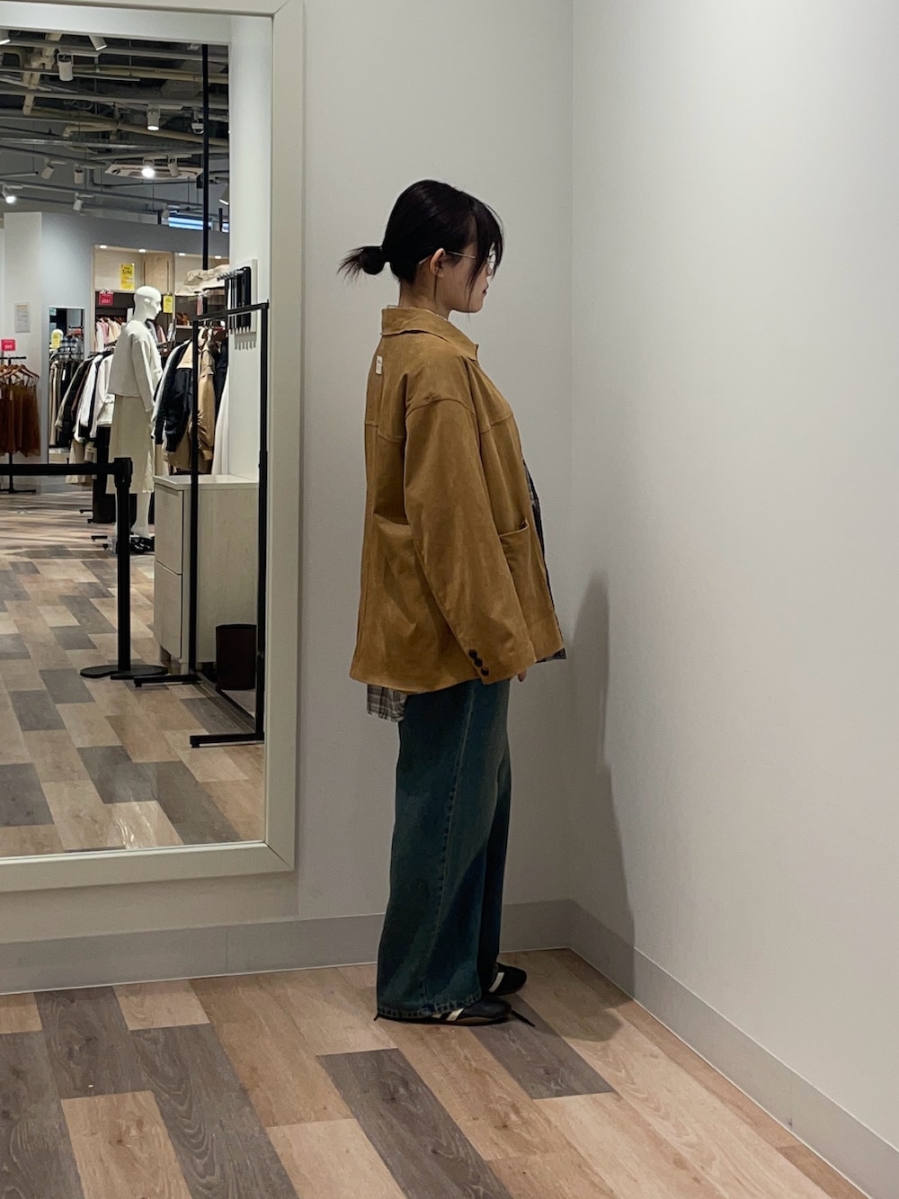 イエロー系のブルゾン、ホワイト系のシャツ/ブラウス、ブルー系のデニムパンツを着用したレディースの冬コーディネートの2枚目の写真