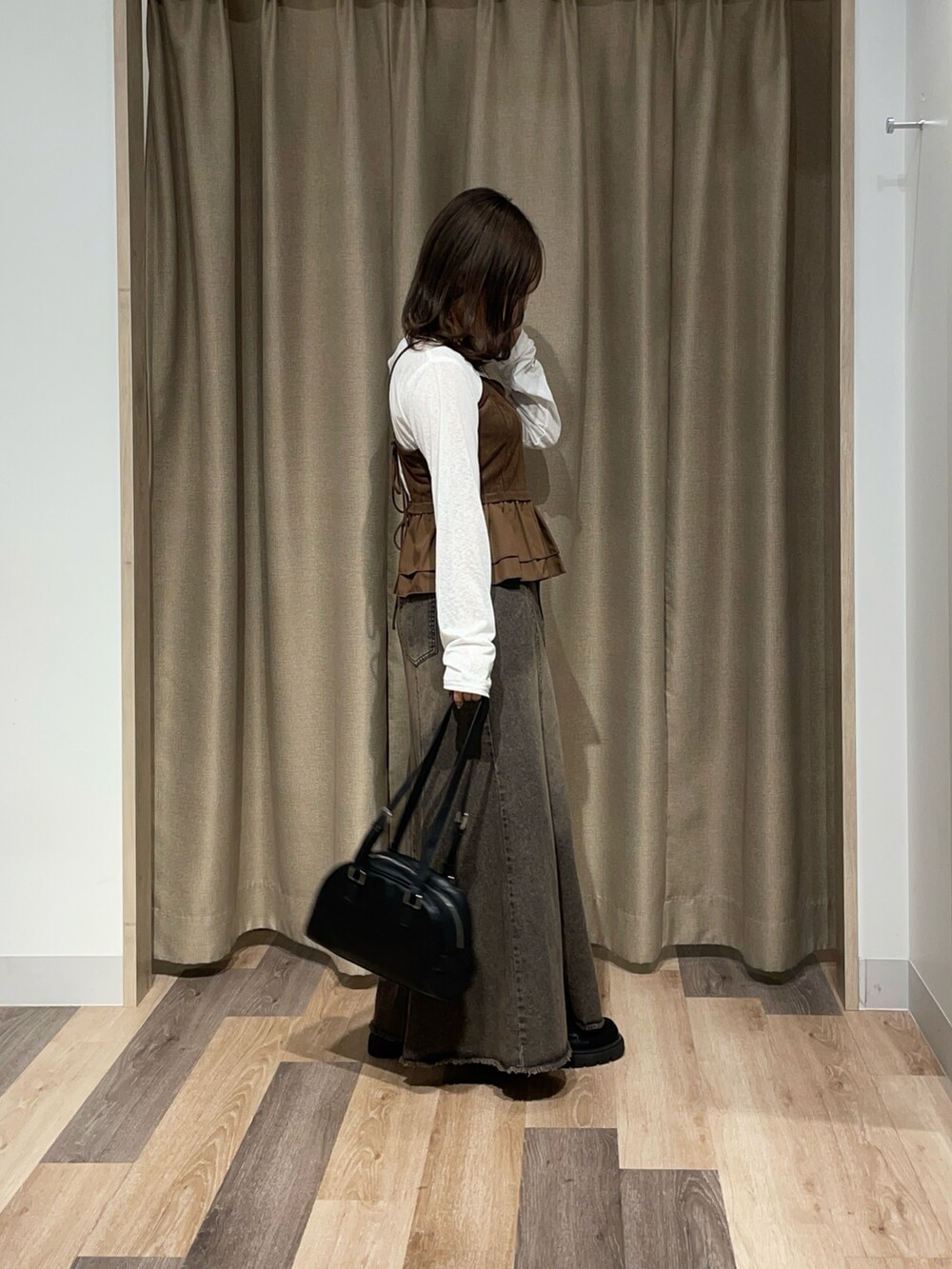 ホワイト系のTシャツ/カットソー、ブルー系のスカート、ブラウン系のボストンバッグを着用したレディースの秋コーディネートの2枚目の写真