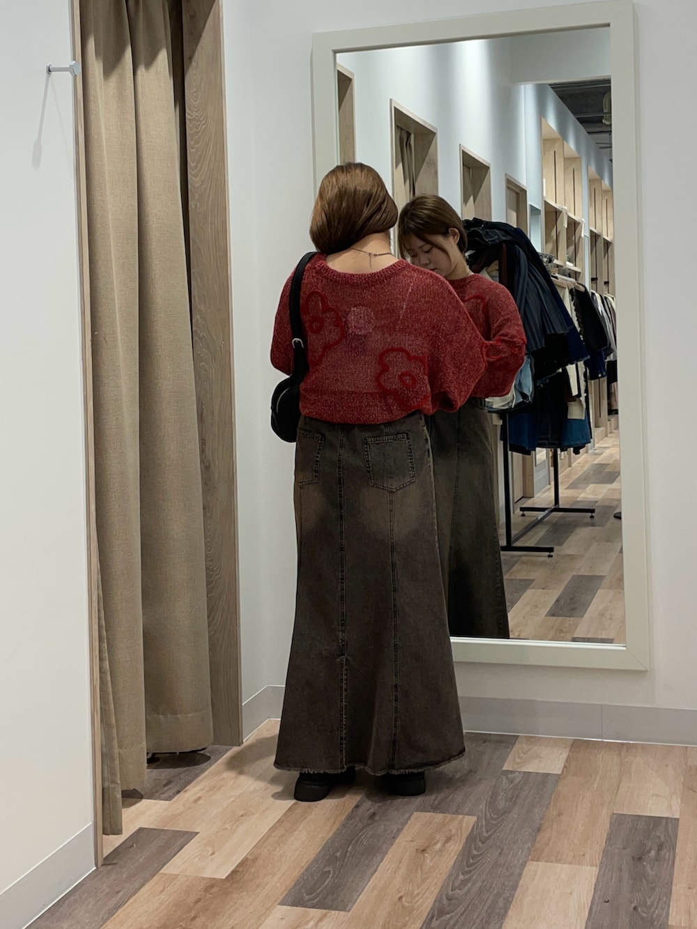 レッド系のニット/セーター、ブラック系のスカート、ブラウン系のボストンバッグを着用したレディースの秋コーディネートの3枚目の写真