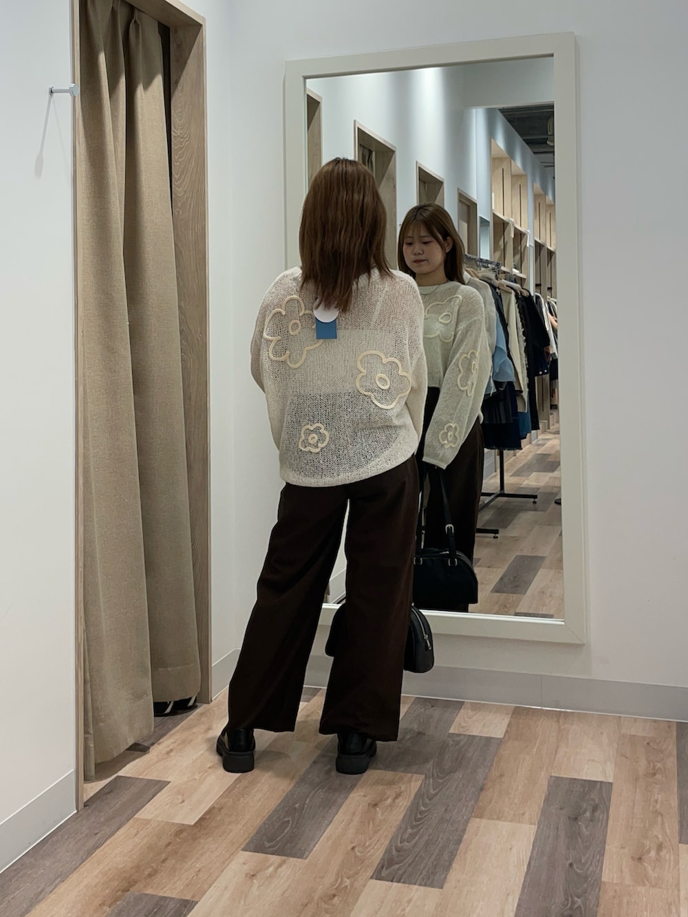 レッド系のニット/セーター、ブラック系のスラックス、ブラウン系のボストンバッグを着用したレディースの秋コーディネートの3枚目の写真