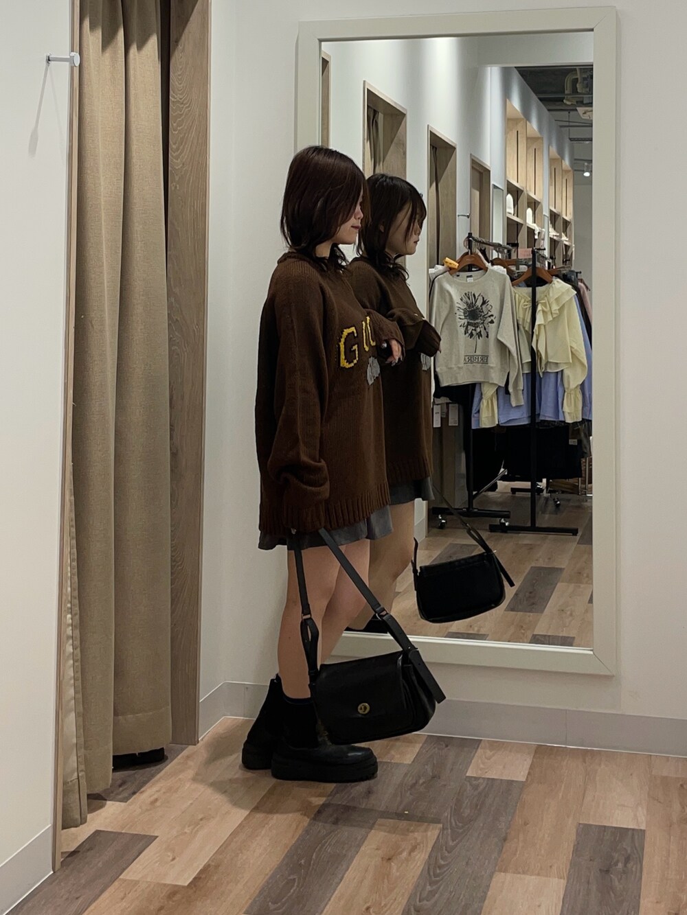 ブラック系のブーツ、ブラウン系のニット/セーター、ブラック系のトートバッグを着用したレディースの秋コーディネートの2枚目の写真