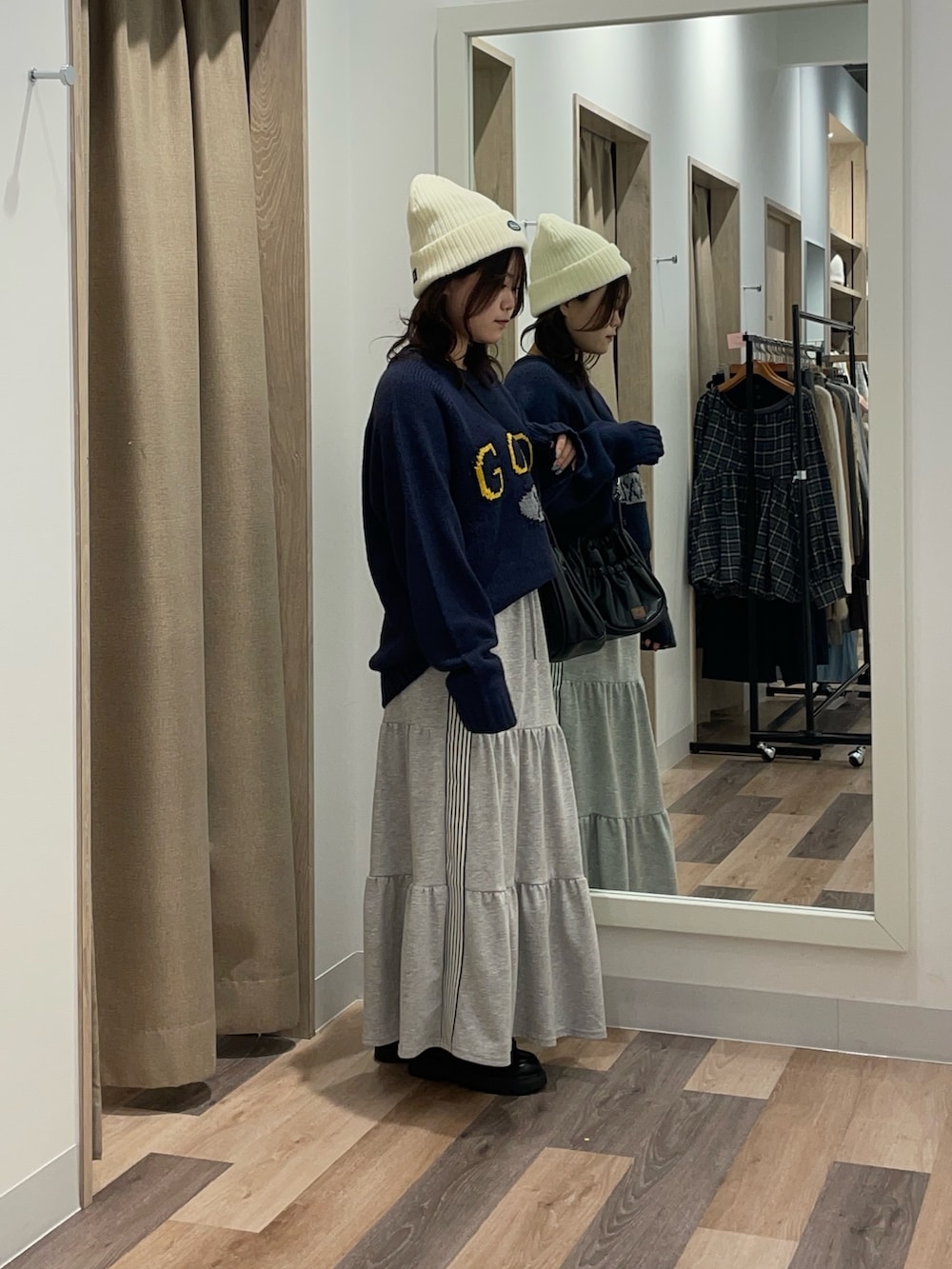 ブルー系のニット/セーター、グレー系のスカートを着用したレディースの秋コーディネートの2枚目の写真