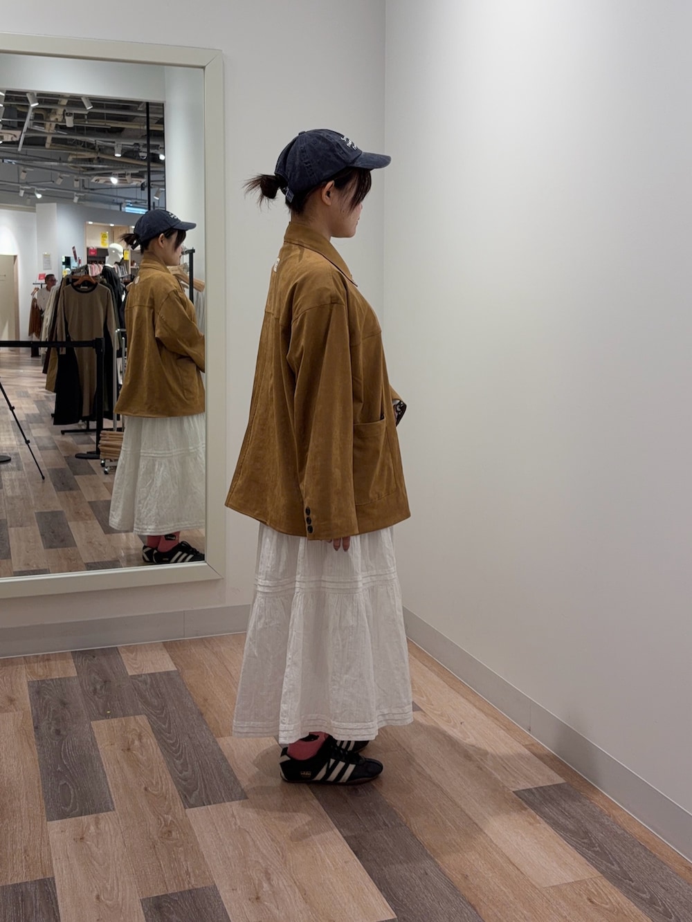 イエロー系のブルゾン、ホワイト系のスカートを着用したレディースの冬コーディネートの2枚目の写真