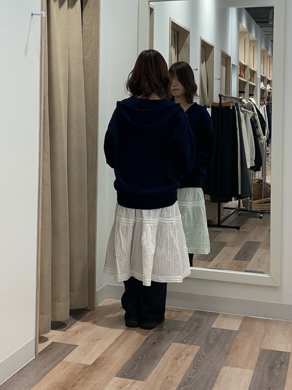 グレー系のニット/セーター、ホワイト系のスカート、ブラック系のデニムパンツを着用したレディースの冬コーディネートの3枚目の写真