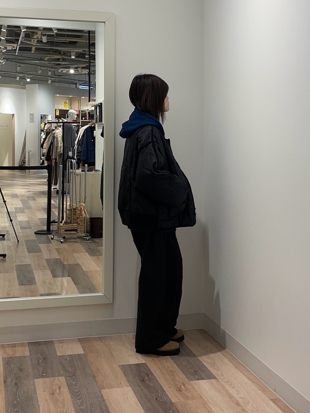 ブラック系のブルゾン、ブルー系のパーカー、ブラック系のスラックスを着用したレディースの冬コーディネートの2枚目の写真