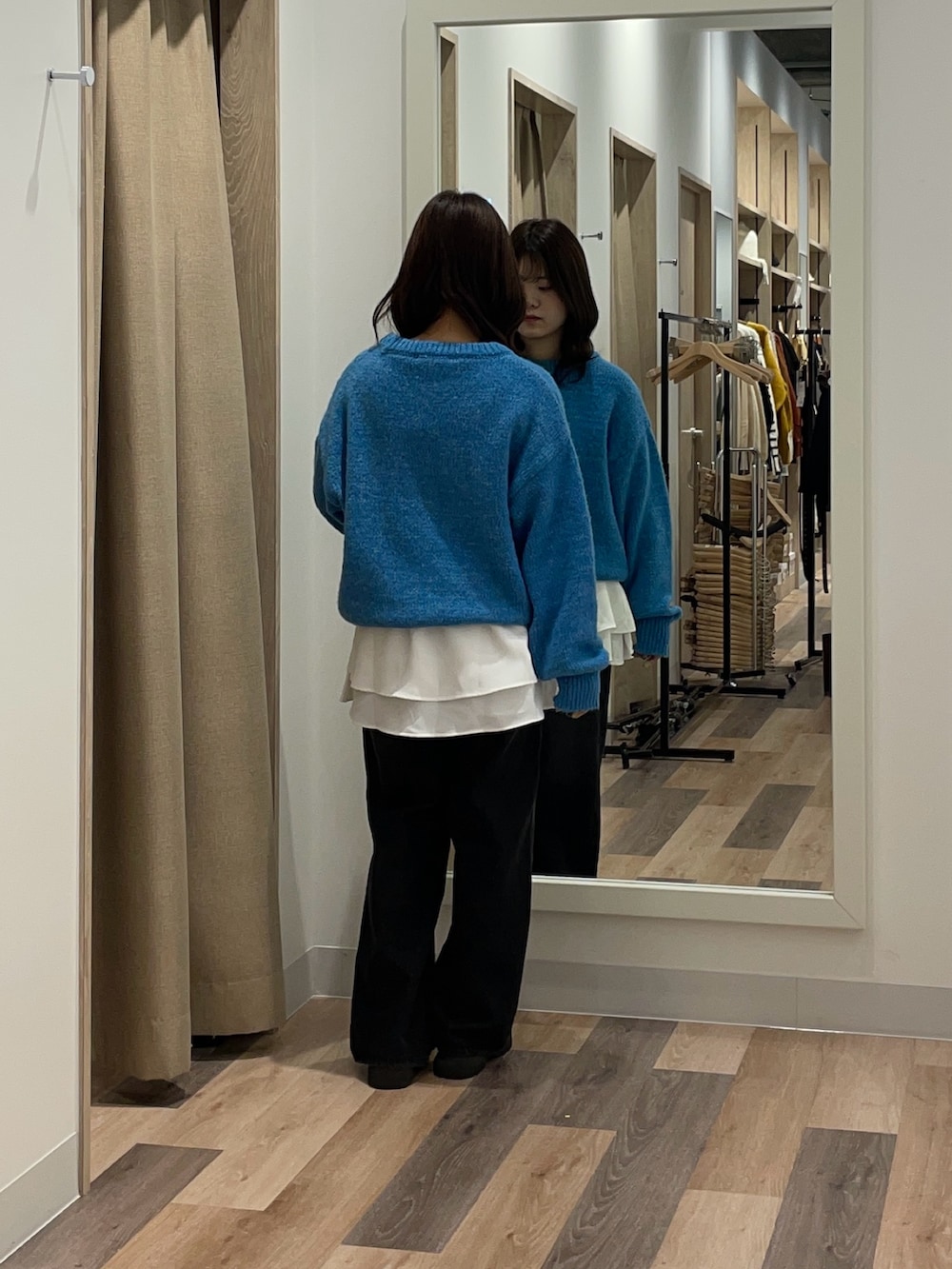 ブルー系のニット/セーター、ブラック系のデニムパンツ、ホワイト系のTシャツ/カットソーを着用したレディースの秋コーディネートの3枚目の写真