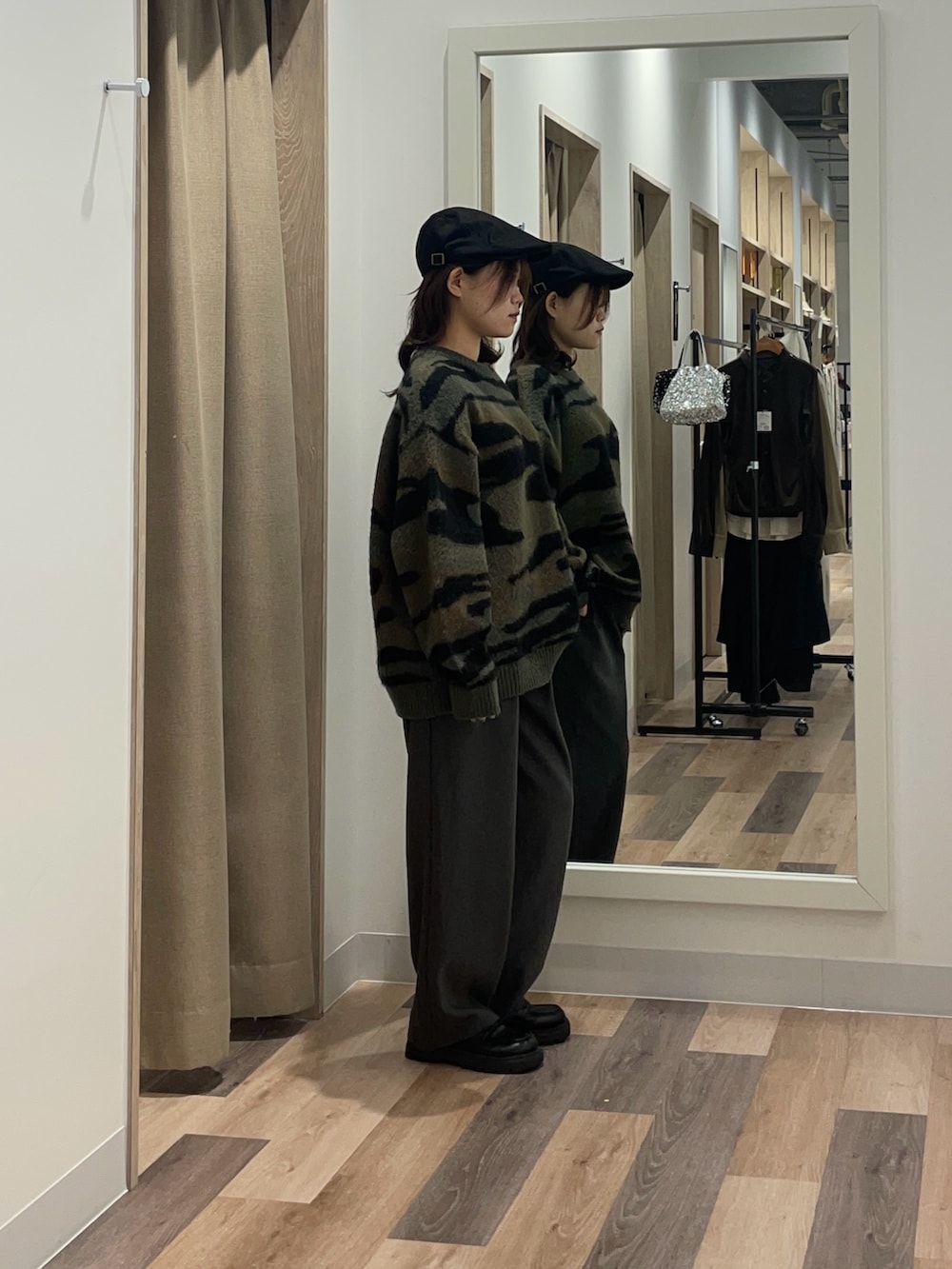 グリーン系のニット/セーター、グレー系のスラックスを着用したレディースの冬コーディネートの2枚目の写真