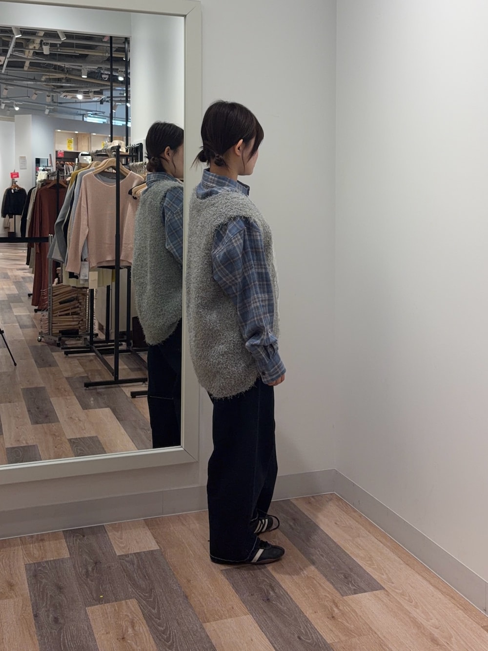 ブルー系のシャツ/ブラウス、グレー系のニット/セーター、ブルー系のデニムパンツを着用したレディースの春コーディネートの2枚目の写真