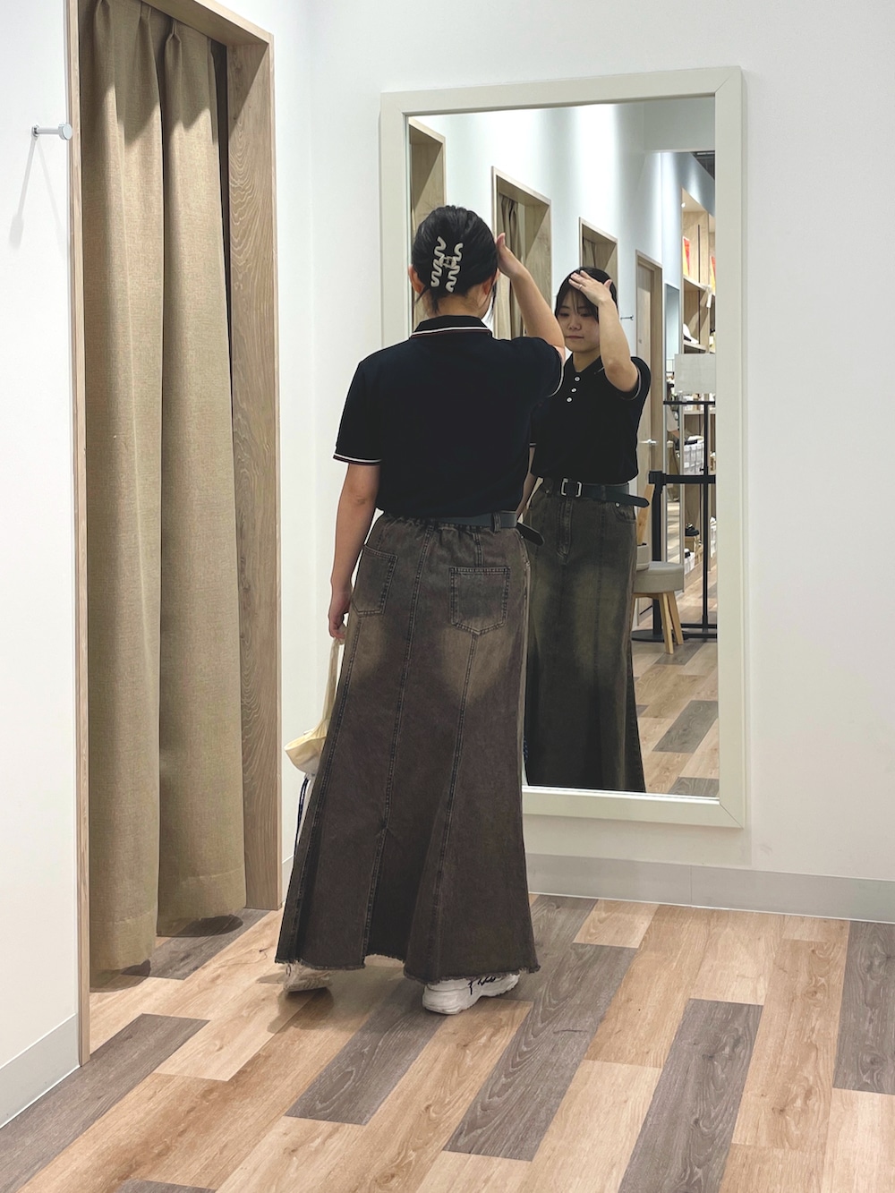 ベージュ系のポロシャツ、ブラック系のスカート、ホワイト系のトートバッグを着用したレディースの夏コーディネートの3枚目の写真