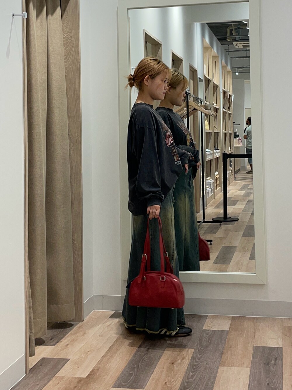 ブルー系のスカート、ブラウン系のボストンバッグ、ブラック系のTシャツ/カットソーを着用したレディースの夏コーディネートの2枚目の写真