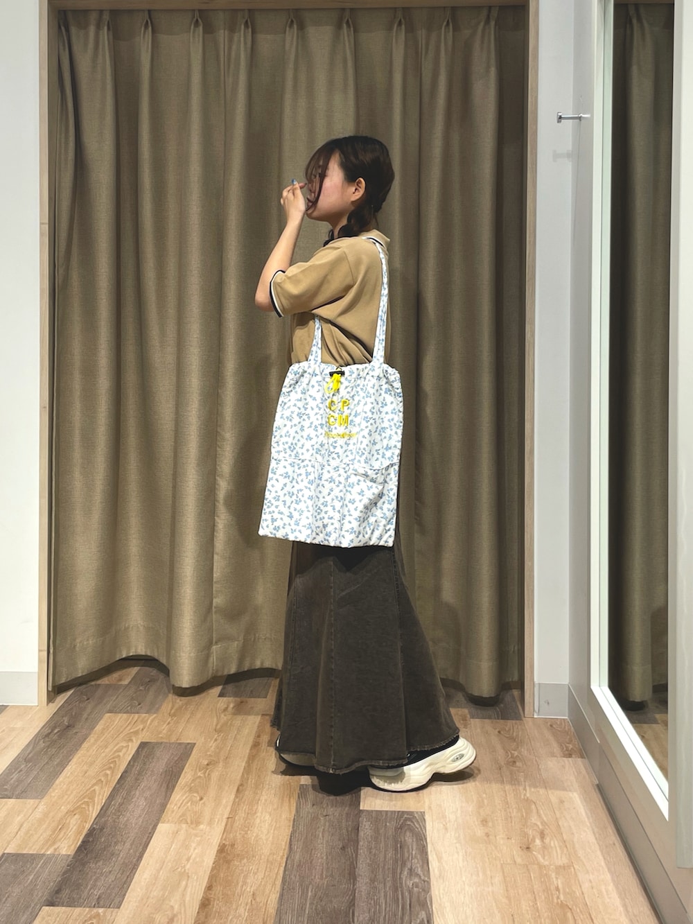 ベージュ系のポロシャツ、ブラック系のスカート、ブラック系のトートバッグを着用したレディースの夏コーディネートの2枚目の写真