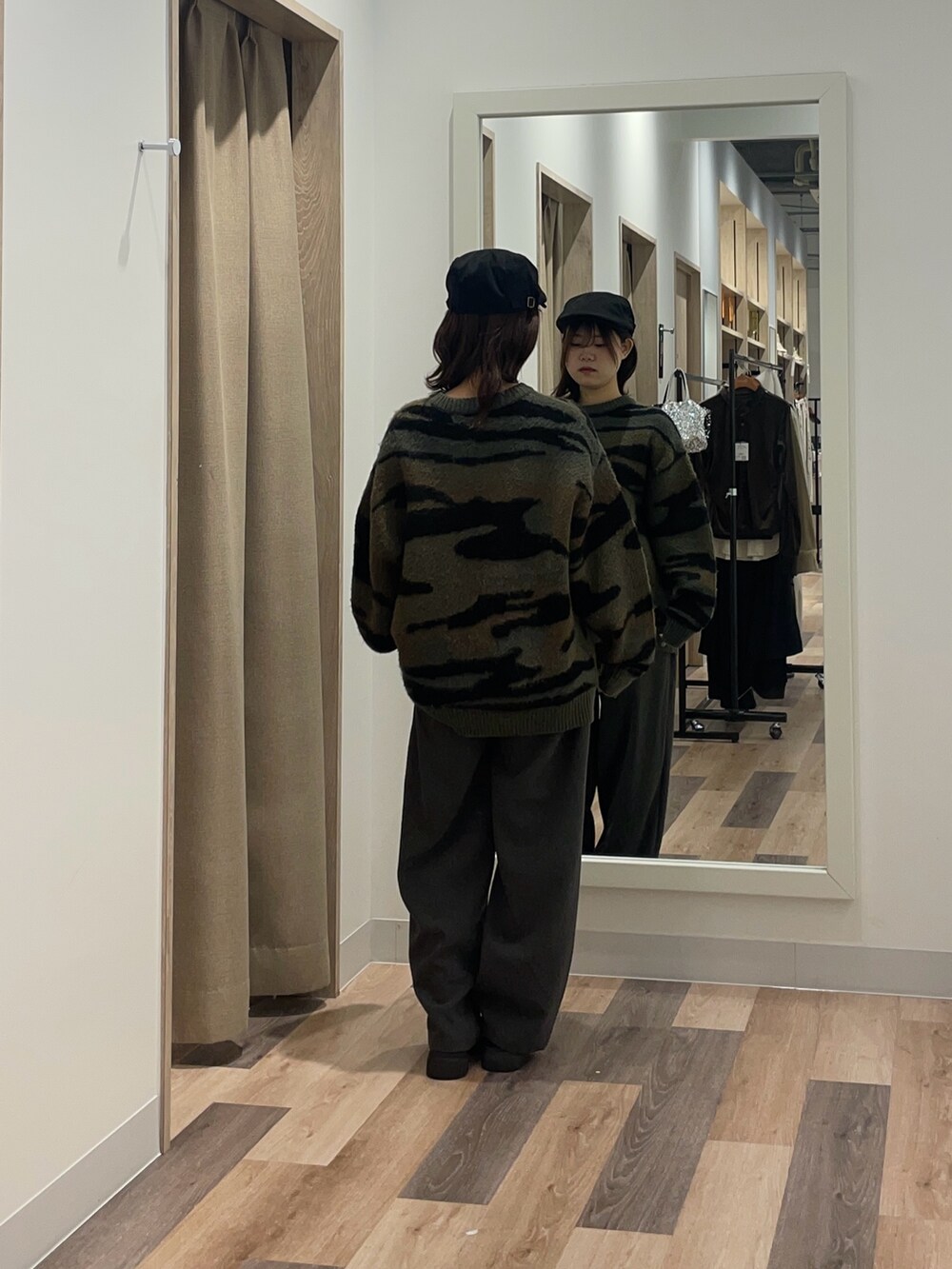 グリーン系のニット/セーター、グレー系のスラックスを着用したレディースの冬コーディネートの3枚目の写真