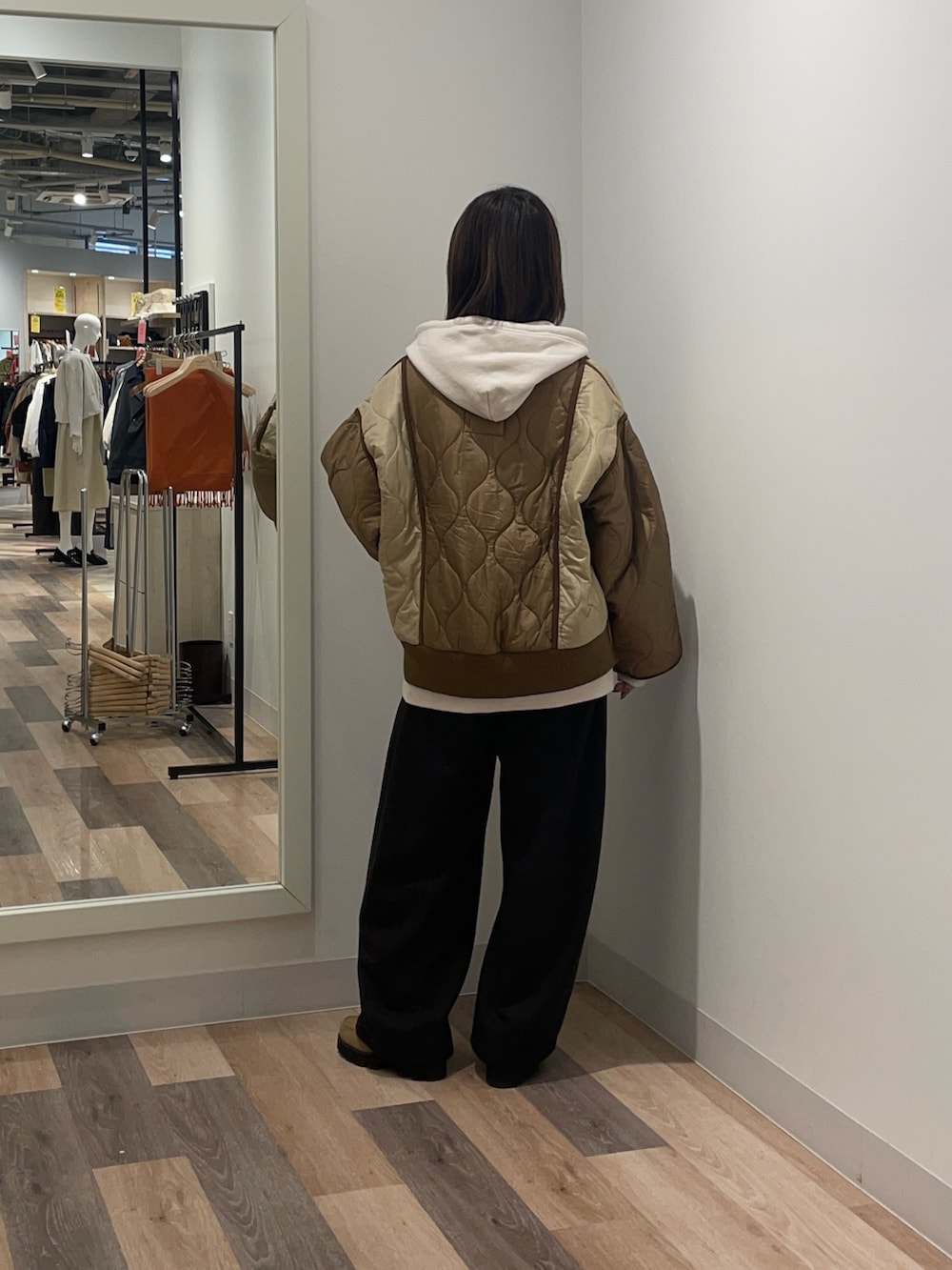 ベージュ系のブルゾン、ホワイト系のパーカー、ブラック系のスラックスを着用したレディースの冬コーディネートの3枚目の写真